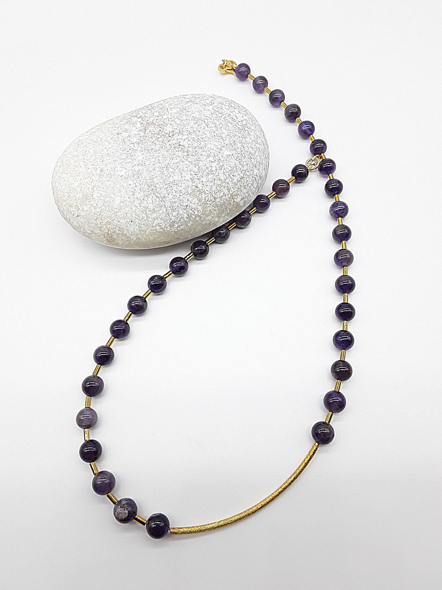 Close-up of Polmadeva Renewal Arc Necklace – golden brushed silver arc with amethyst stones