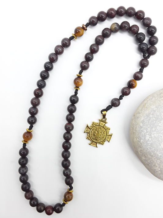 Bloodstone pocket Catholic rosary with Saint Benedict cross placed beside natural stone
