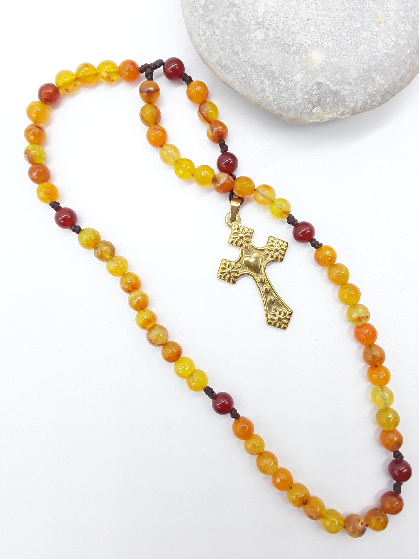 Agate and Carnelian pocket Catholic rosary placed beside natural stone, steel crucifix visible