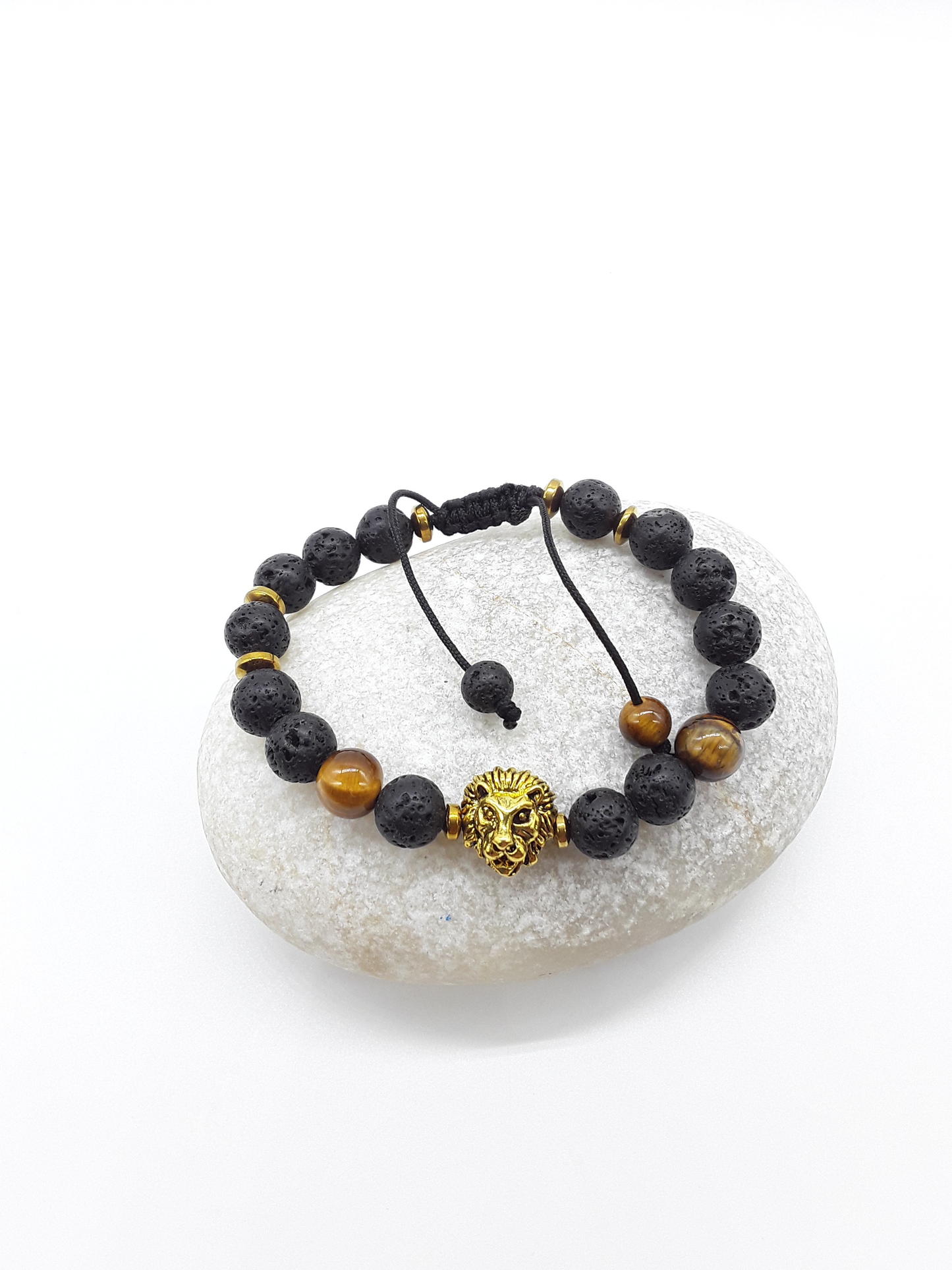 Holdfast beaded bracelet with lion symbol resting on natural stone, quiet luxury editorial style