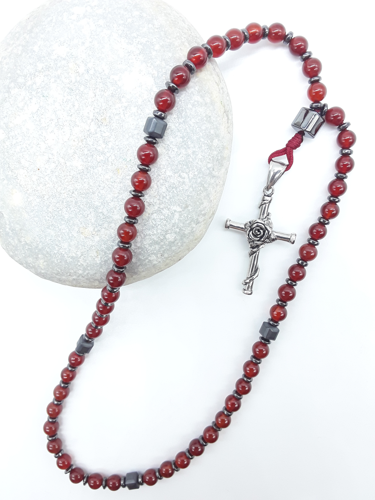 Carnelian and Hematite Orthodox Rosary with stainless steel cross resting on natural stone surface by Polmadeva.