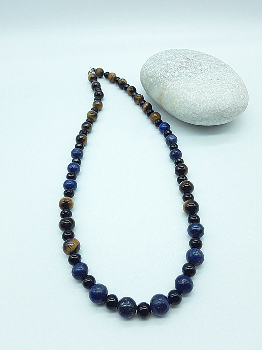 Polmadeva Quiet Sentinel Necklace with lapis lazuli, tiger’s eye and black onyx beads shown in full length beside natural stone, Guardian Spirit collection