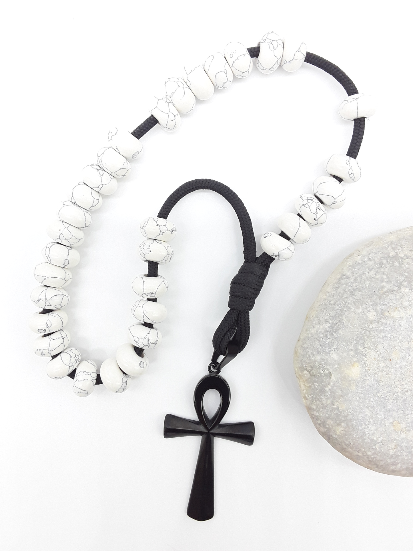 Howlite Paracord Orthodox Rosary with black Ankh cross beside natural stone surface by Polmadeva.