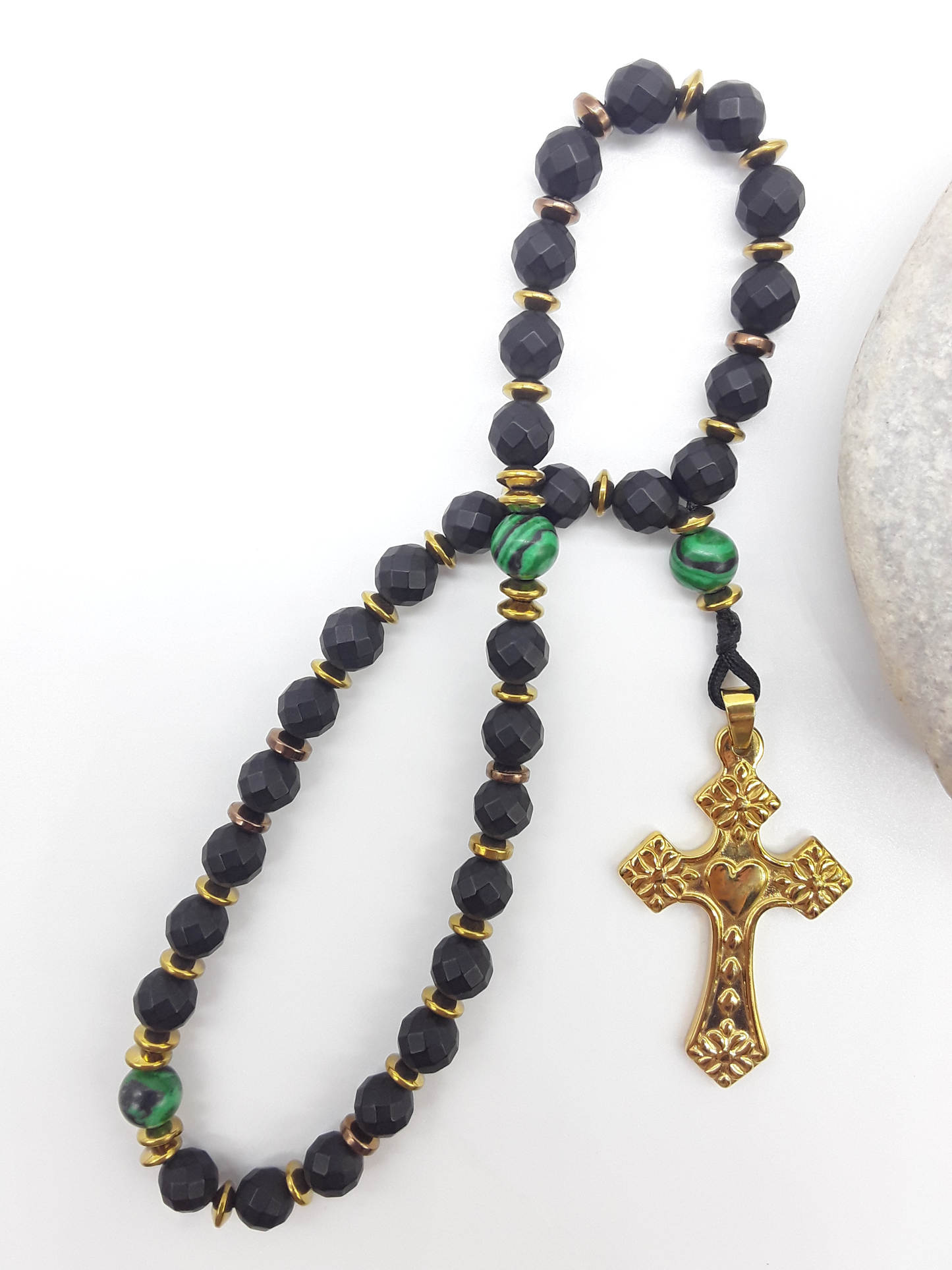 The Verdant Vigil — Black Onyx & Malachite Orthodox Rosary by Polmadeva, faceted black onyx beads with malachite accents and stainless steel cross, photographed beside natural stone to emphasize clarity, vigilance, and grounded presence.
