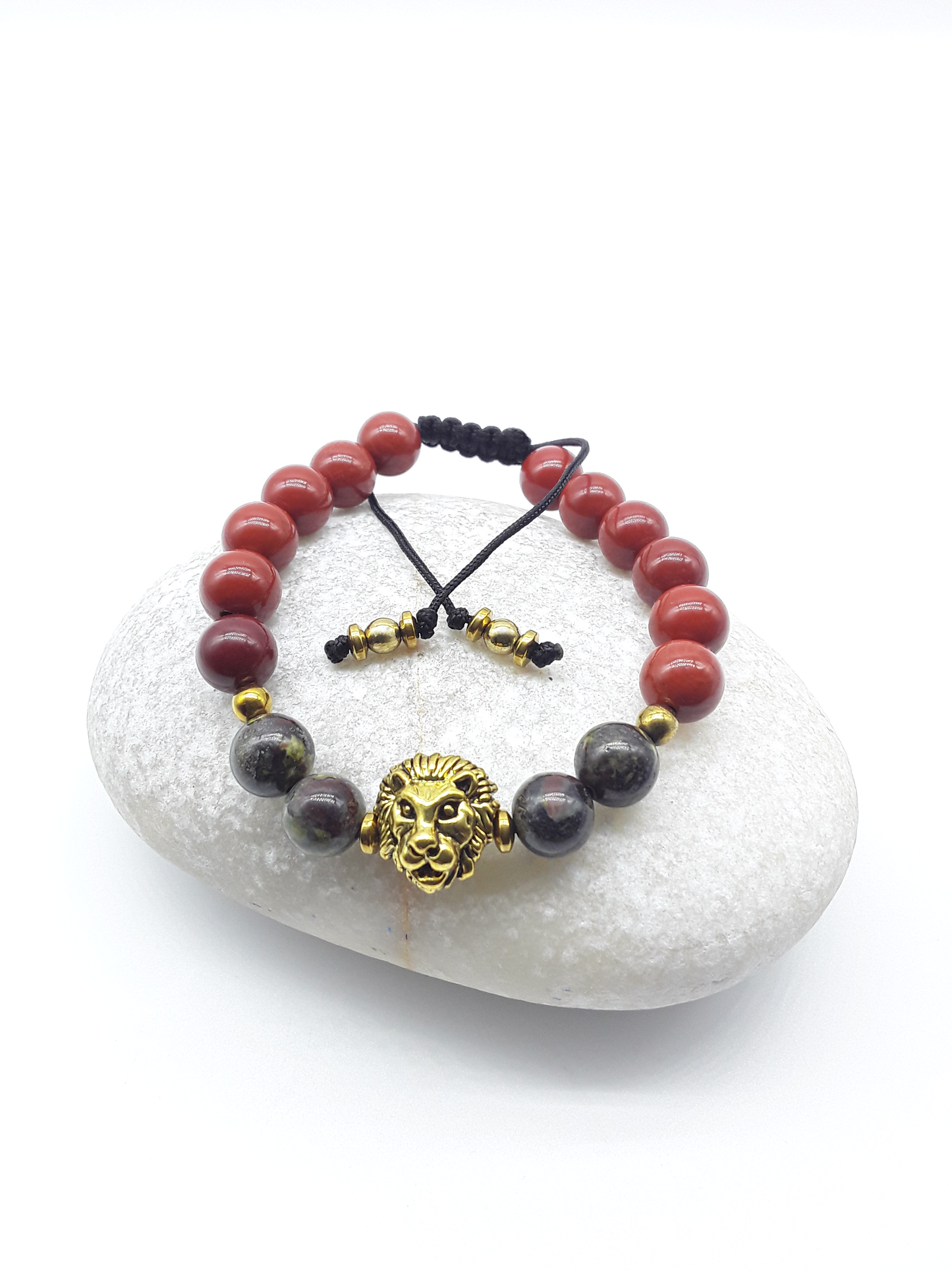 Lion bracelet with red jasper and dragon blood stones resting on a natural stone surface