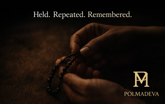 Hands gently holding a rosary in low light, emphasizing repetition, touch, and quiet remembrance.