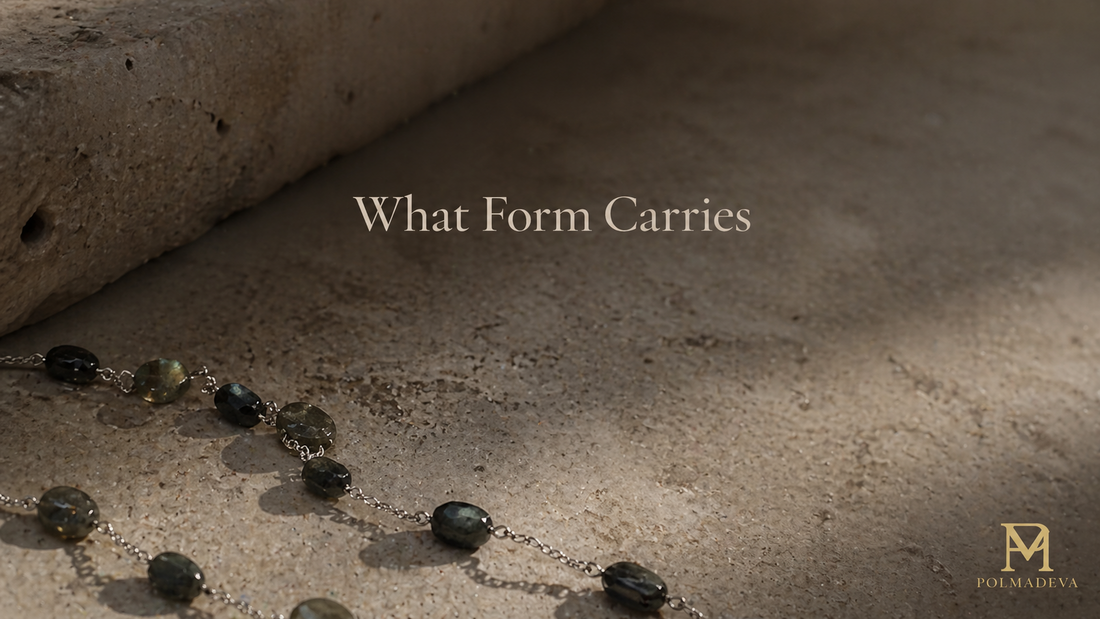 Partial view of a stone necklace resting on a textured surface under soft natural light, with the title “What Form Carries” centered above and Polmadeva logo at the bottom right.