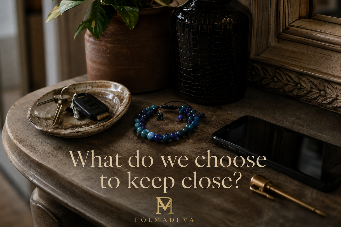 Editorial lifestyle scene of a Polmadeva bracelet resting beside everyday items on an entryway table, with the quote “What do we choose to keep close?” in elegant serif typography and the Polmadeva logo below.