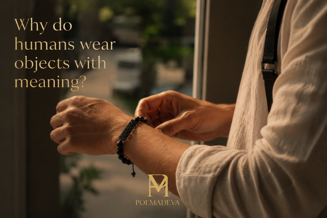 A close, natural moment of a person adjusting a bracelet on their wrist in soft daylight, with the text “Why do humans wear objects with meaning?” and the Polmadeva logo.