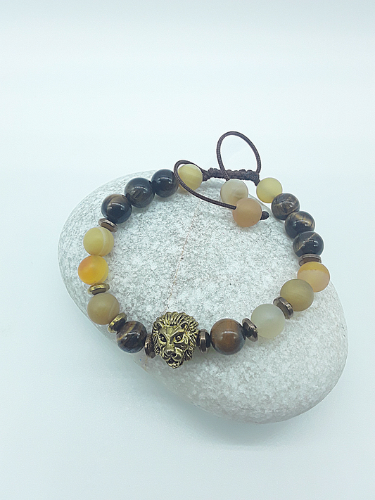 Handcrafted lion bracelet with Tiger’s Eye, Agate, and Hematite beads resting on a natural stone surface by Polmadeva.