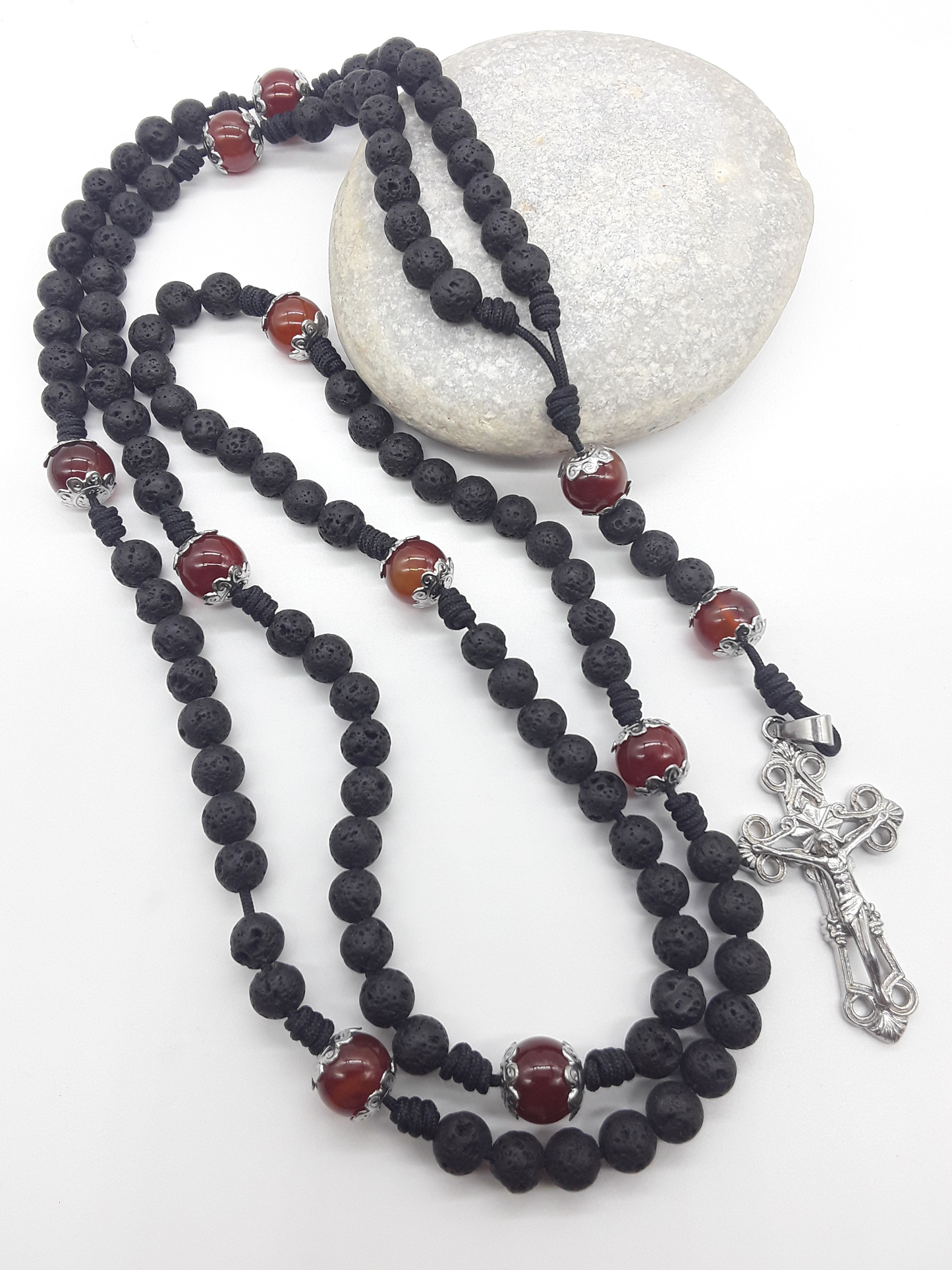 Carried Through Time lava stone and carnelian 10-decade Catholic rosary resting on stone by Polmadeva