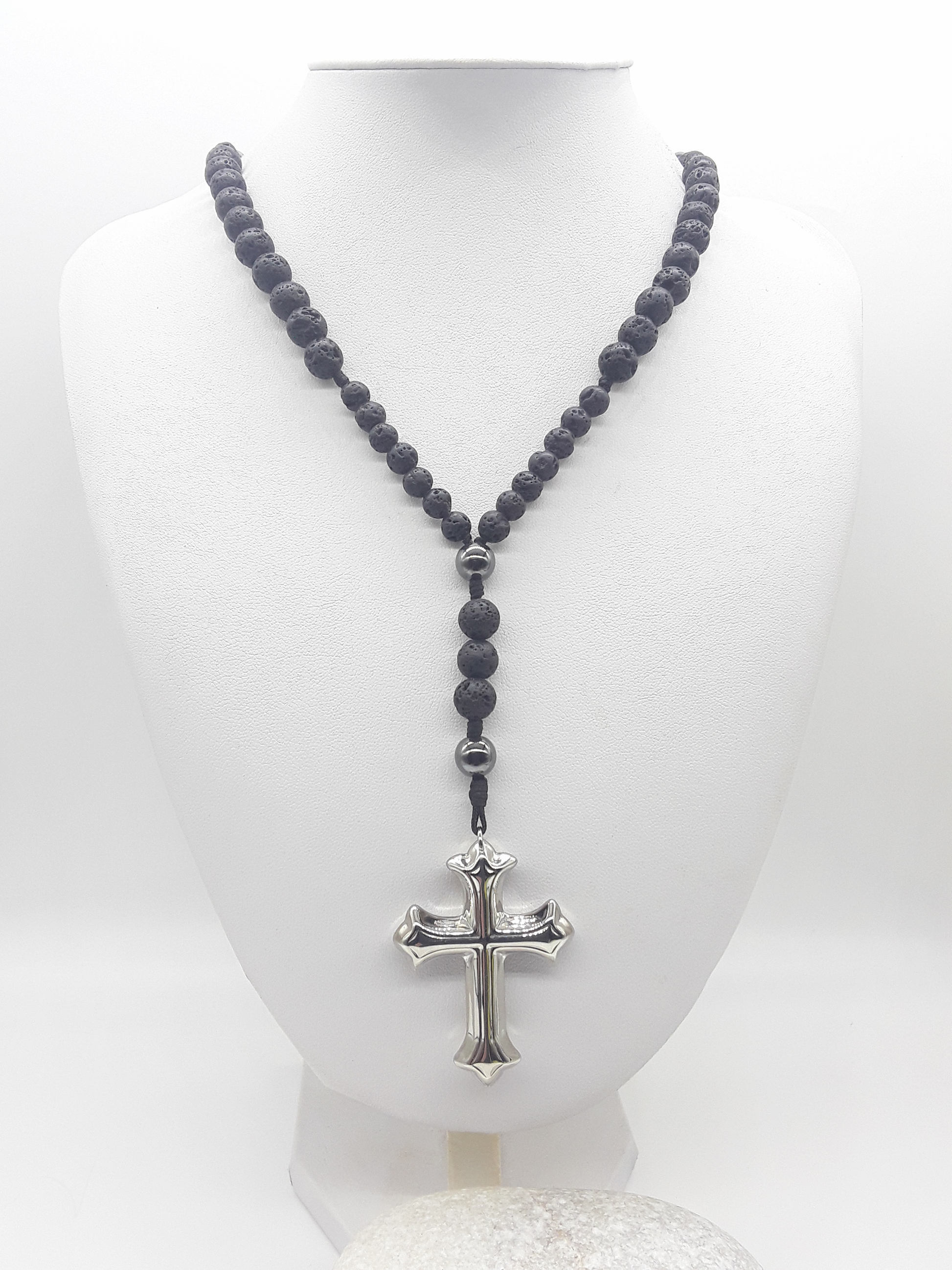 Traditional Catholic rosary made with lava stone beads, hematite elements, and a sculpted stainless steel cross, displayed on a white bust.