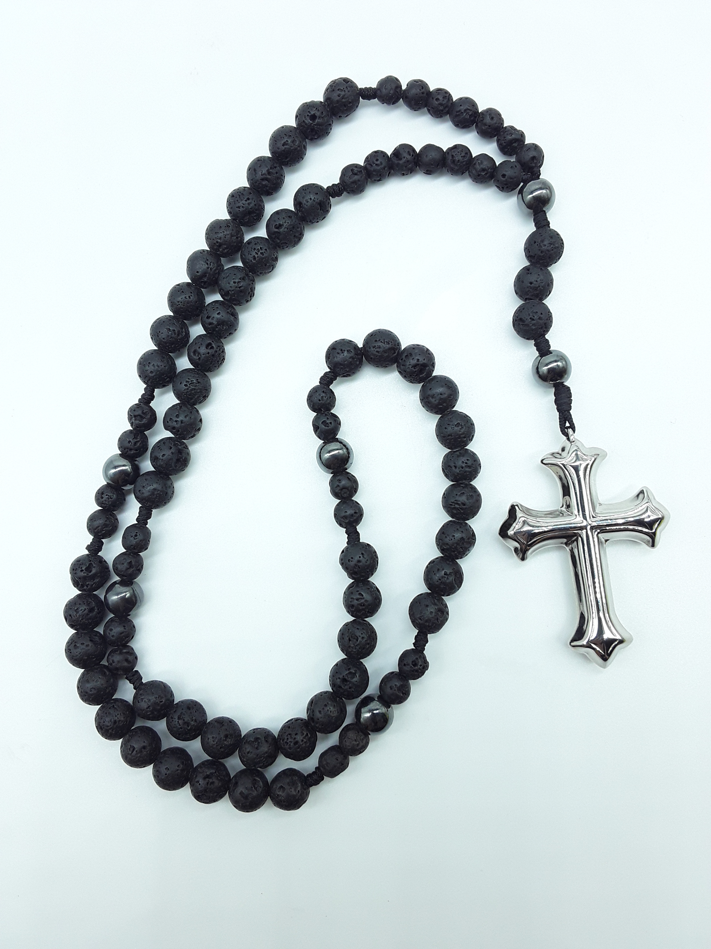 Catholic rosary with lava stone beads, hematite spacers, and a sculpted stainless steel cross shown in full length on a light background.