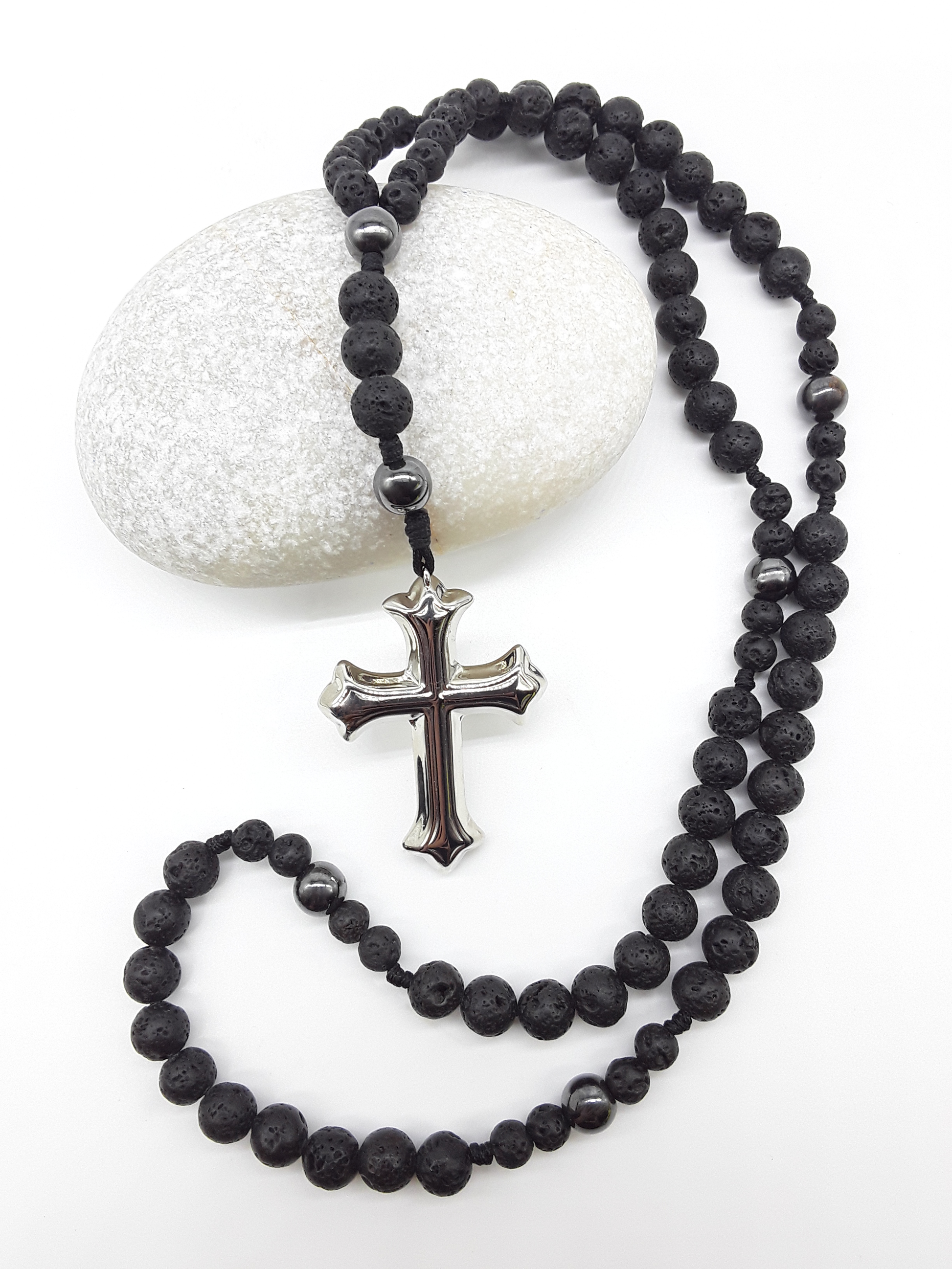 Catholic rosary with lava stone beads, hematite spacers, and a sculpted stainless steel cross shown in full length on a light background.
