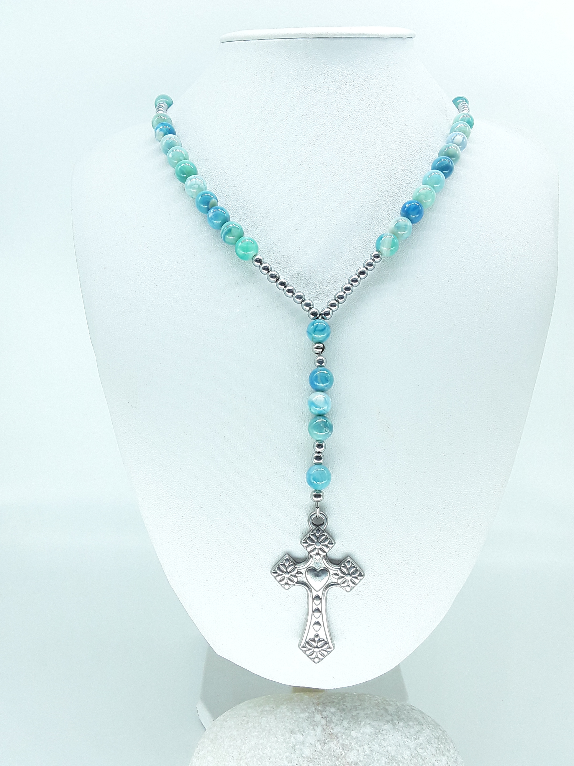 Traditional Catholic rosary made with natural agate beads, hematite spacers, and a stainless steel heart-shaped cross, displayed on a white bust.
