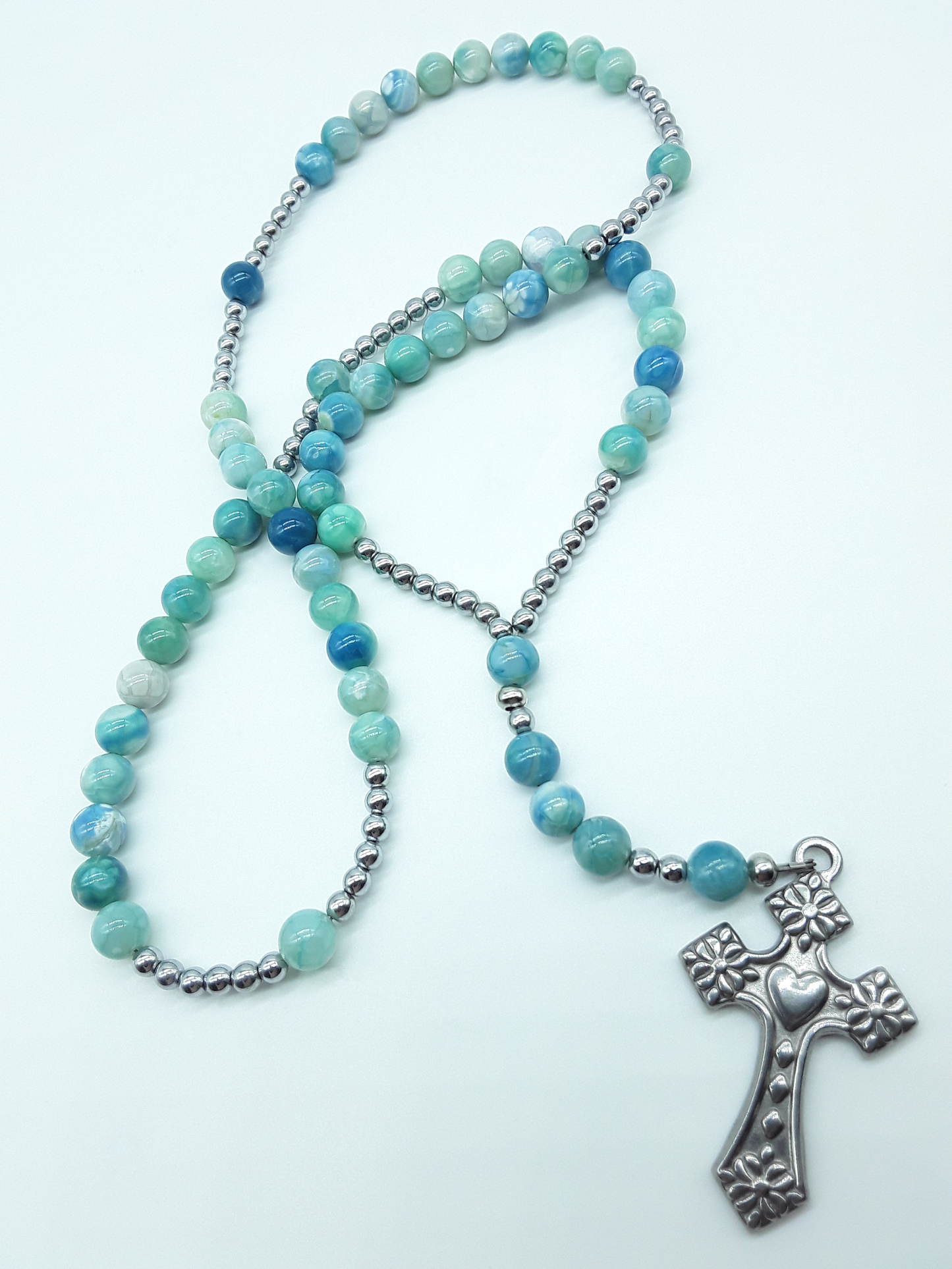 Catholic rosary with natural agate beads, hematite elements, and a stainless steel heart-shaped cross shown in full length on a light background.

