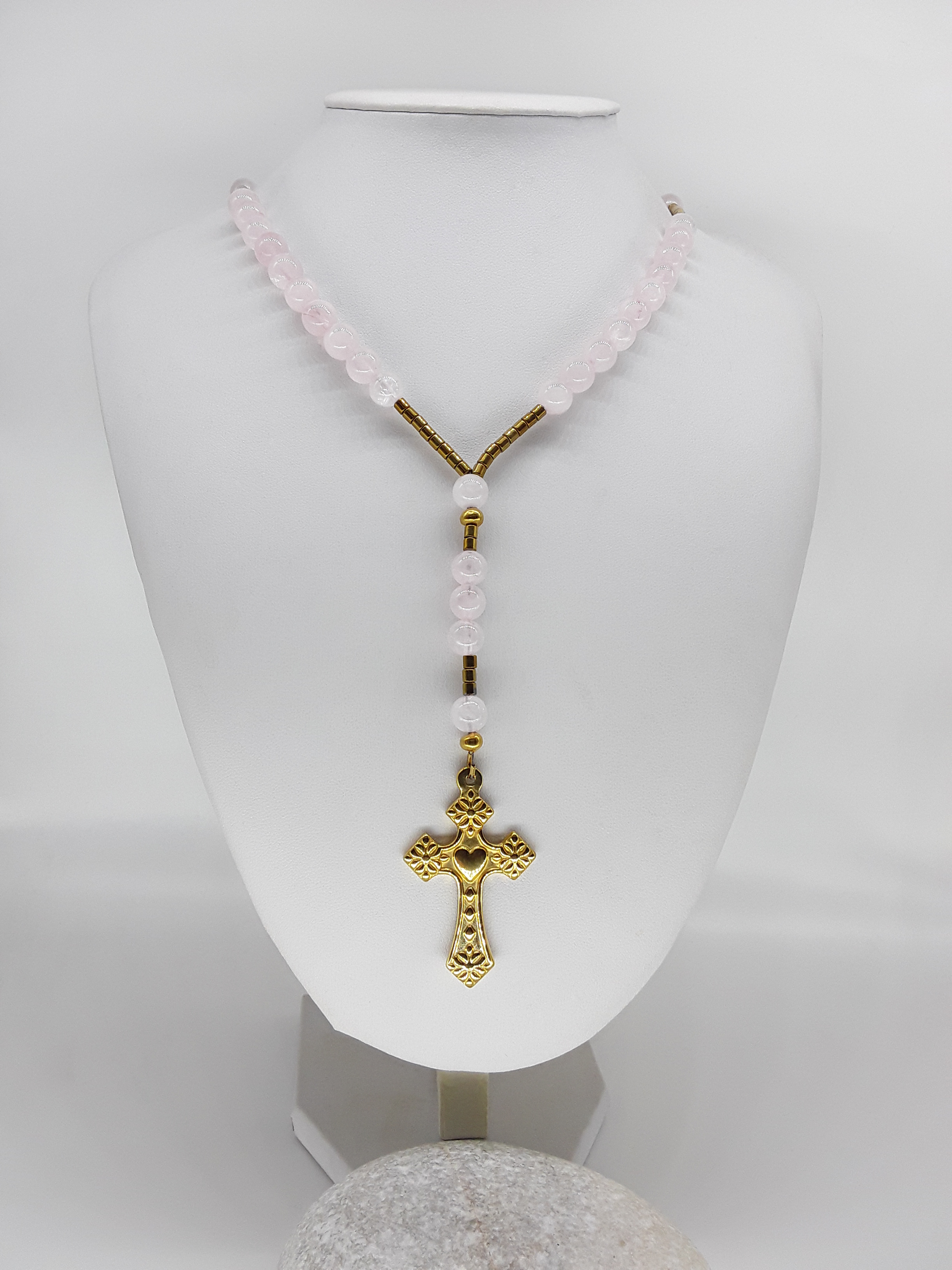 Traditional Catholic rosary made with rose quartz beads, hematite spacers, and a stainless steel heart-shaped cross, displayed on a white bust.