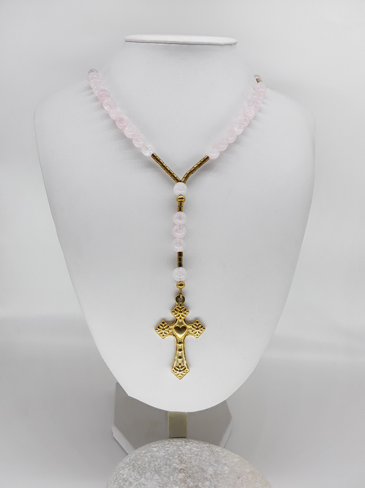 Traditional Catholic rosary made with rose quartz beads, hematite spacers, and a stainless steel heart-shaped cross, displayed on a white bust.