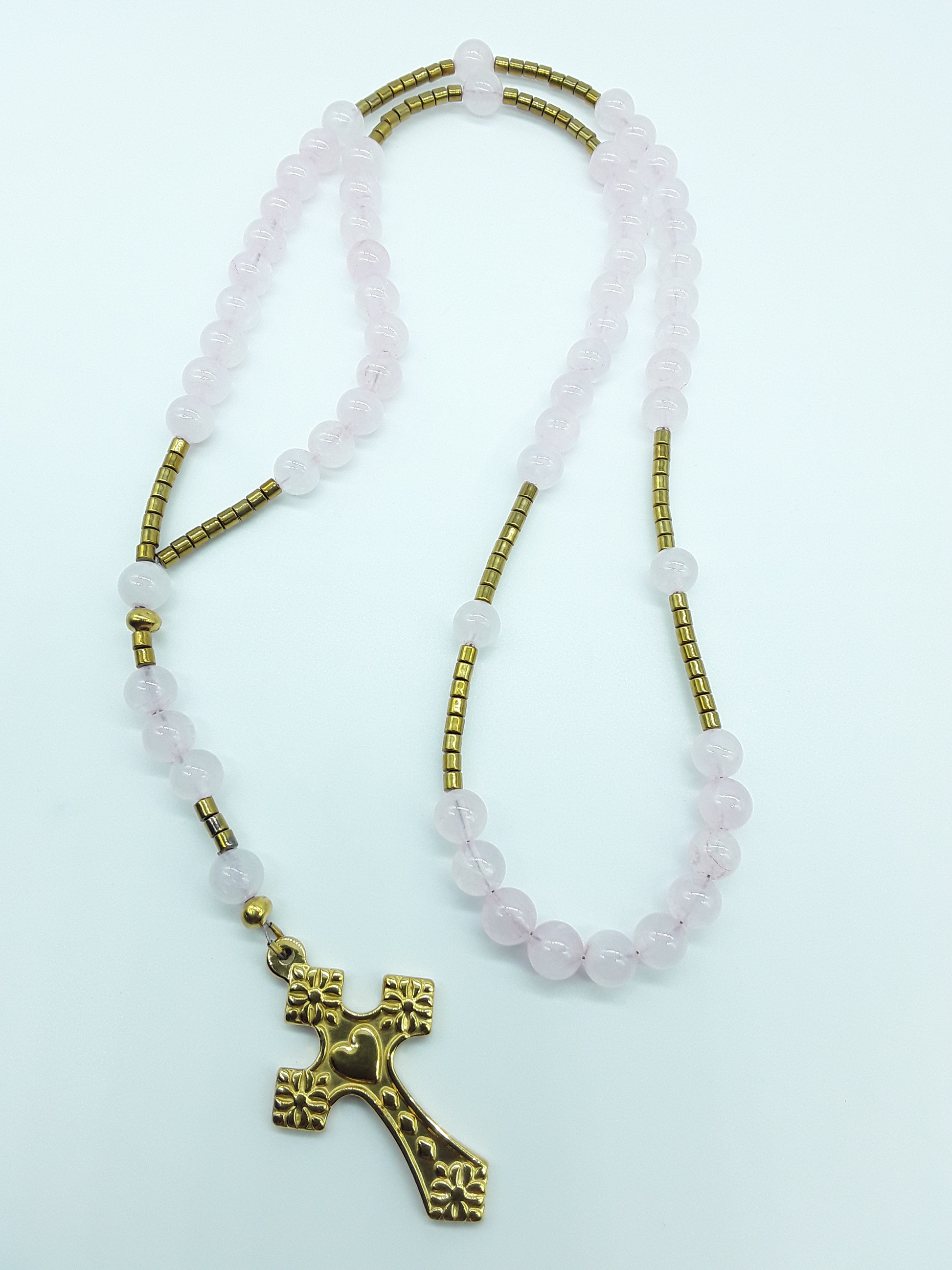 Traditional Catholic rosary with rose quartz beads, hematite elements, and a stainless steel heart-shaped cross shown in full length on a light background.