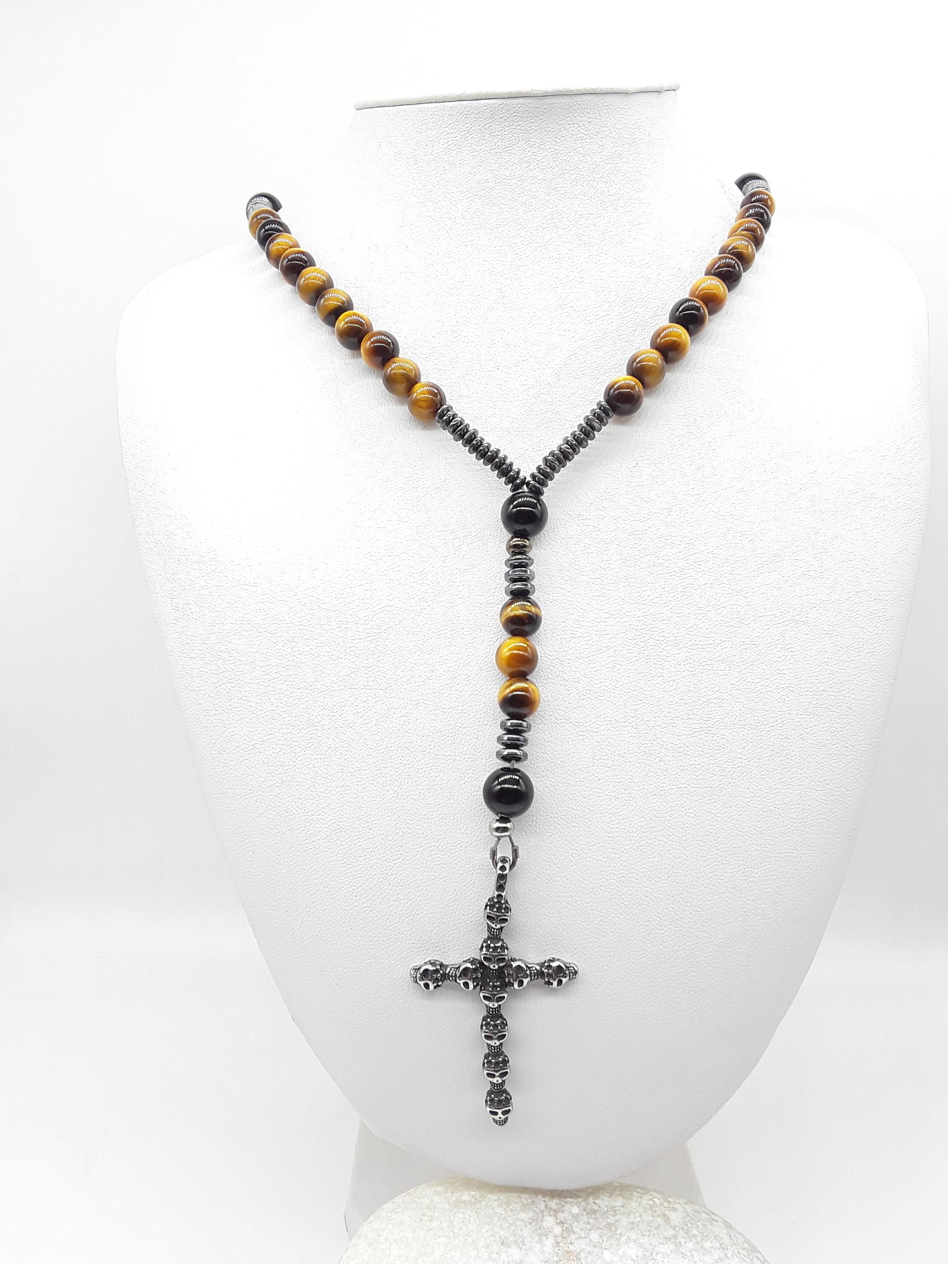 Traditional Catholic rosary made with tiger’s eye beads, black onyx, hematite spacers, and a stainless steel skull cross, displayed on a white bust.