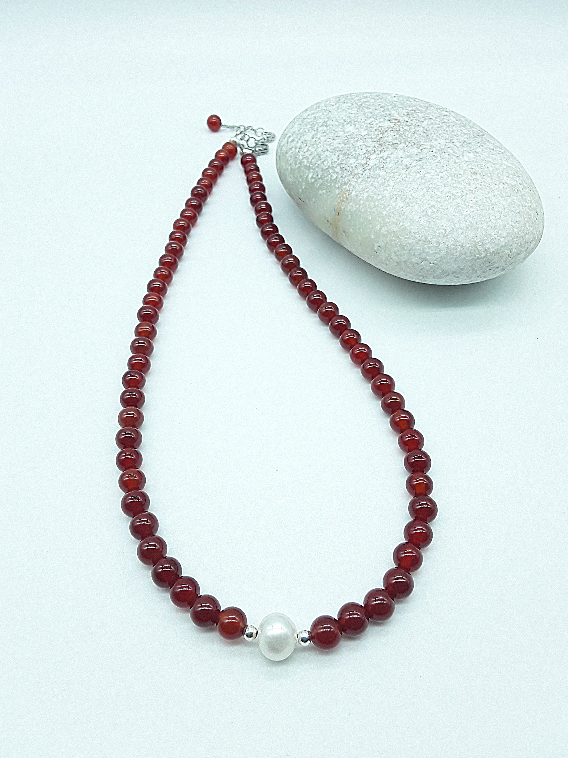 Heartfire Pearl Necklace by Polmadeva laid flat with red carnelian beads, freshwater pearl and silver clasp, Courage Rising collection