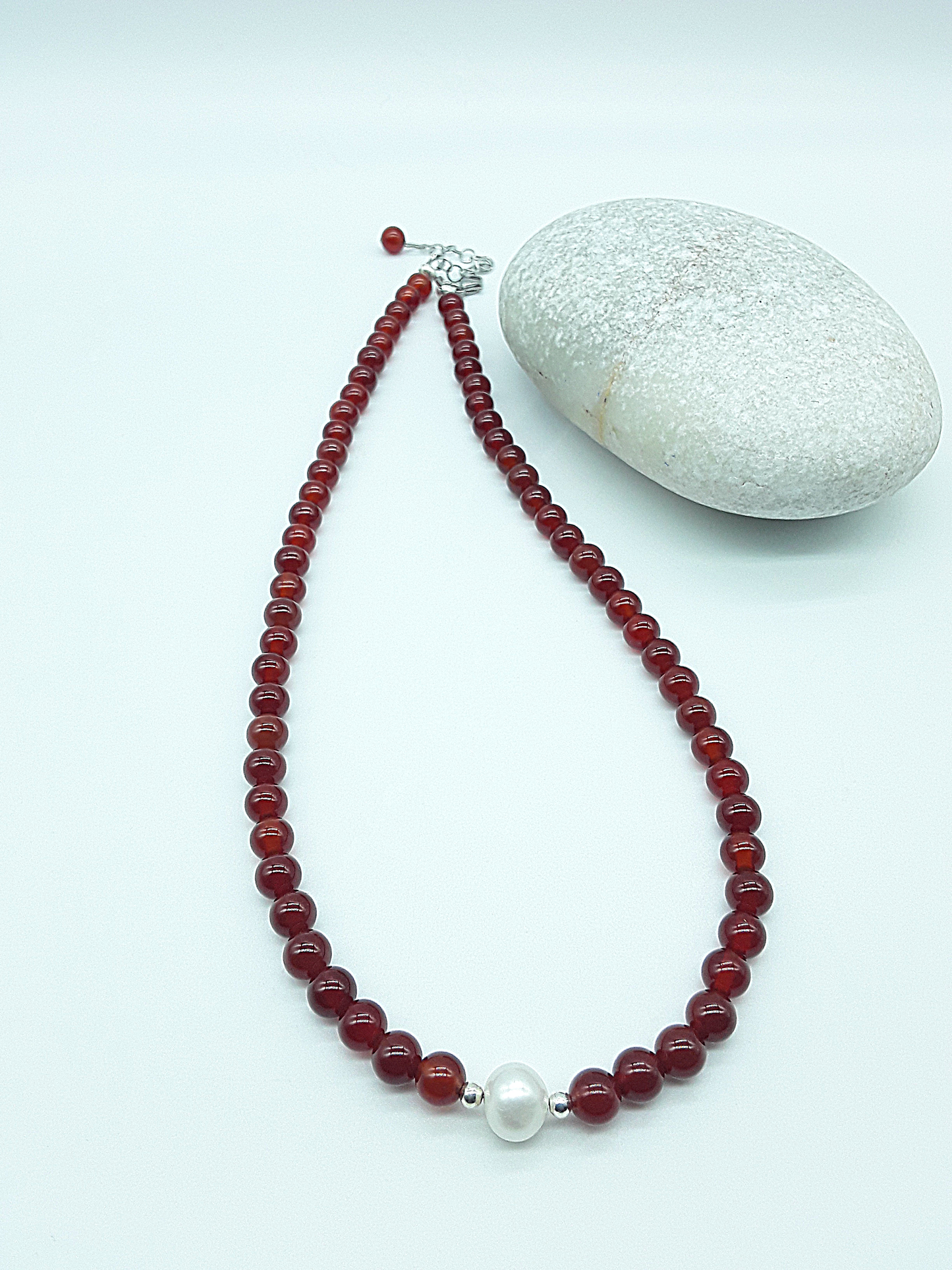 Heartfire Pearl Necklace by Polmadeva laid flat, highlighting red carnelian beads and central freshwater pearl, Courage Rising collection