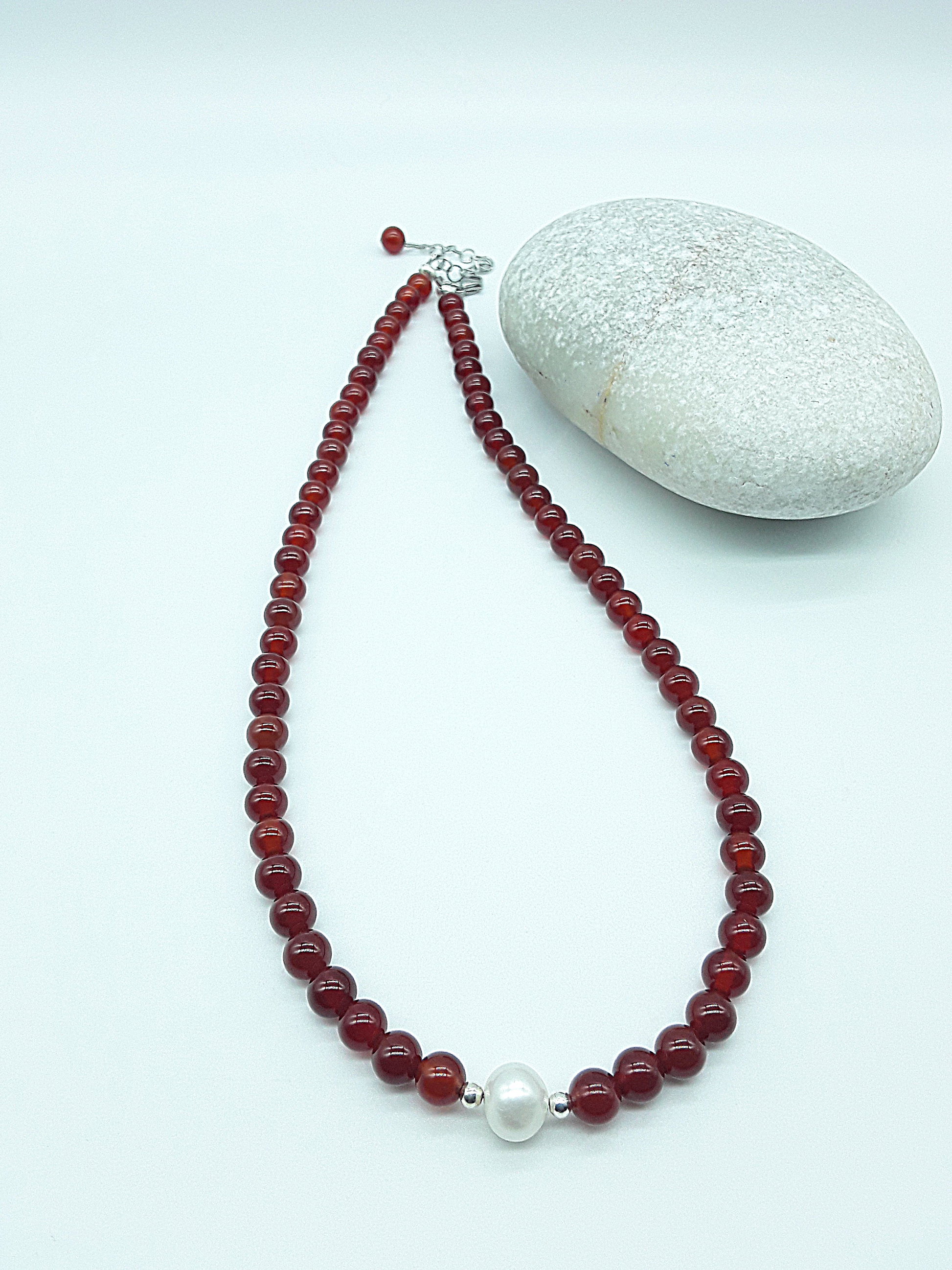 Heartfire Pearl Necklace by Polmadeva laid flat, highlighting red carnelian beads and central freshwater pearl, Courage Rising collection