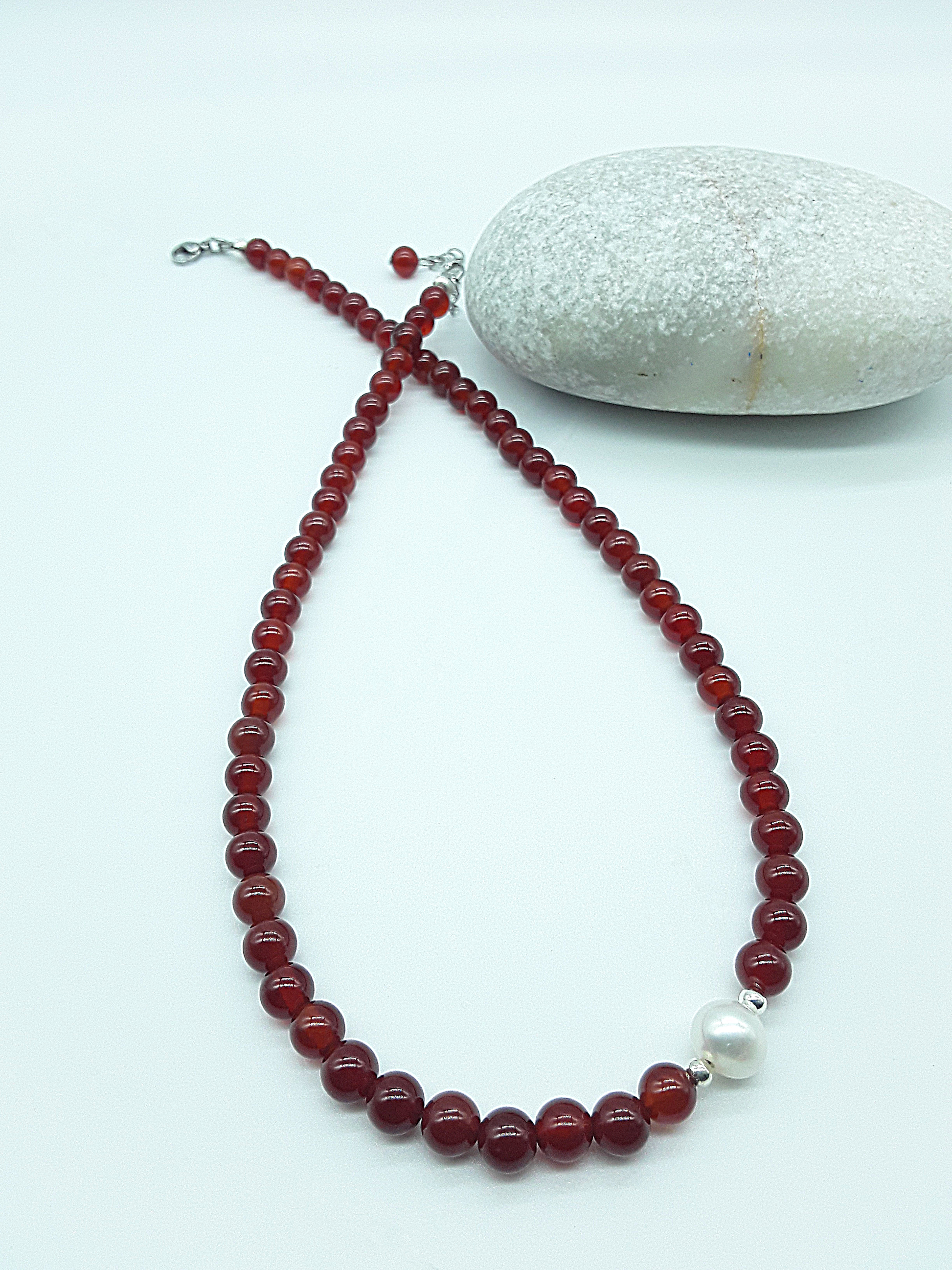 Heartfire Pearl Necklace by Polmadeva laid flat in a vertical flow with red carnelian beads and freshwater pearl, Courage Rising collection