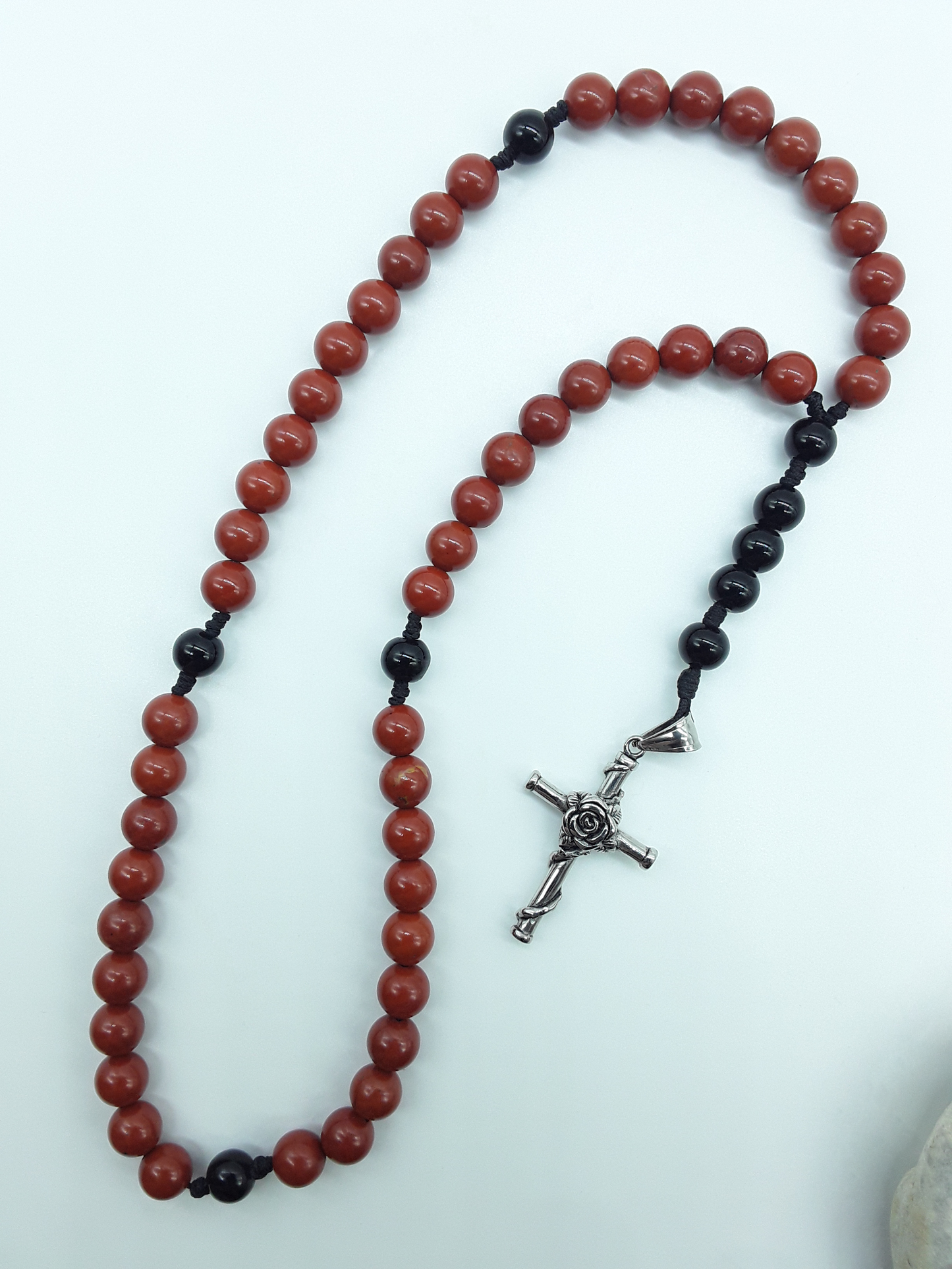 Pocket Catholic Rosary with Red Jasper and Black Onyx beads and a rose-wrapped stainless steel cross on white background.
