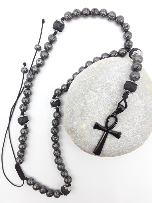 Galvanized Lava Ankh Catholic Rosary with black stainless steel Ankh cross by Polmadeva resting on natural stone surface.