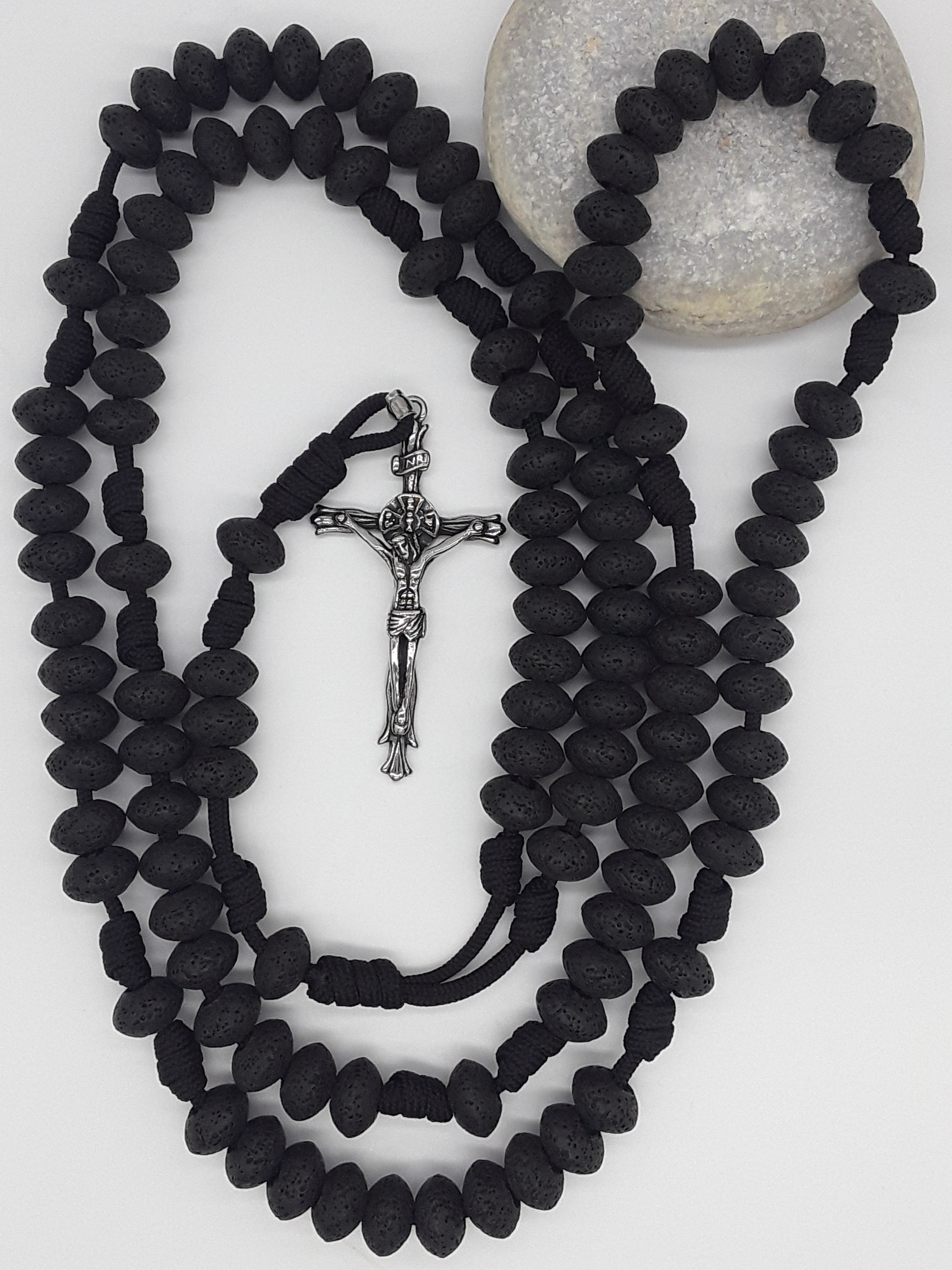 10-decade lava stone Paracord Rosary resting on stone surface, emphasizing physical presence, durability, and continuous Catholic prayer