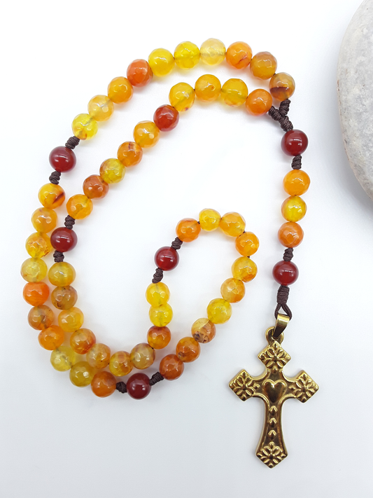Agate and Carnelian pocket Catholic rosary placed beside natural stone, steel crucifix visible