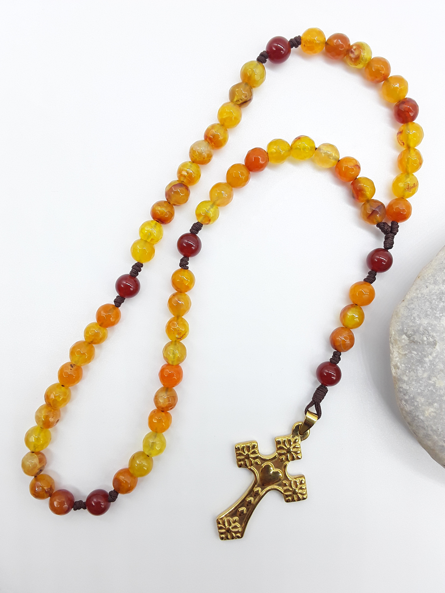 Agate and Carnelian pocket Catholic rosary placed beside natural stone, steel crucifix visible