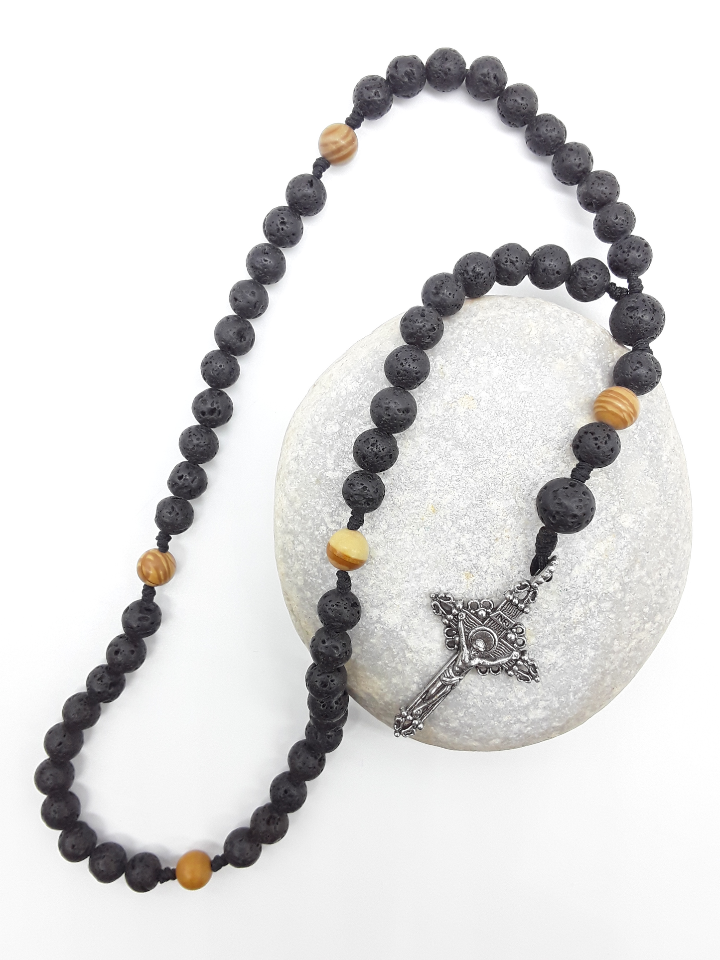 Compact Catholic Pocket Rosary in lava and tigerskin jasper placed on a stone surface, featuring a textured tin crucifix.
