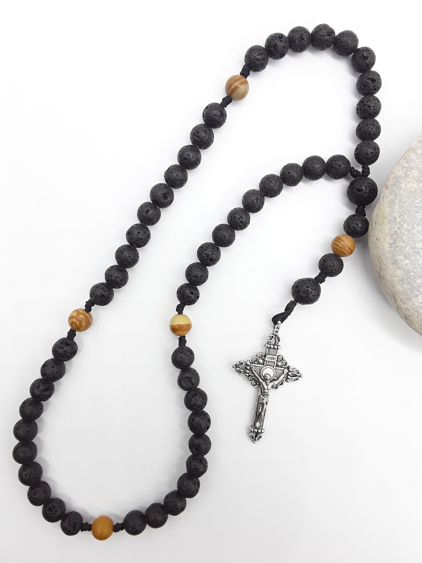 Handcrafted Pocket & Travel Catholic Rosary in lava and tigerskin jasper resting beside a natural stone, with a detailed tin crucifix.