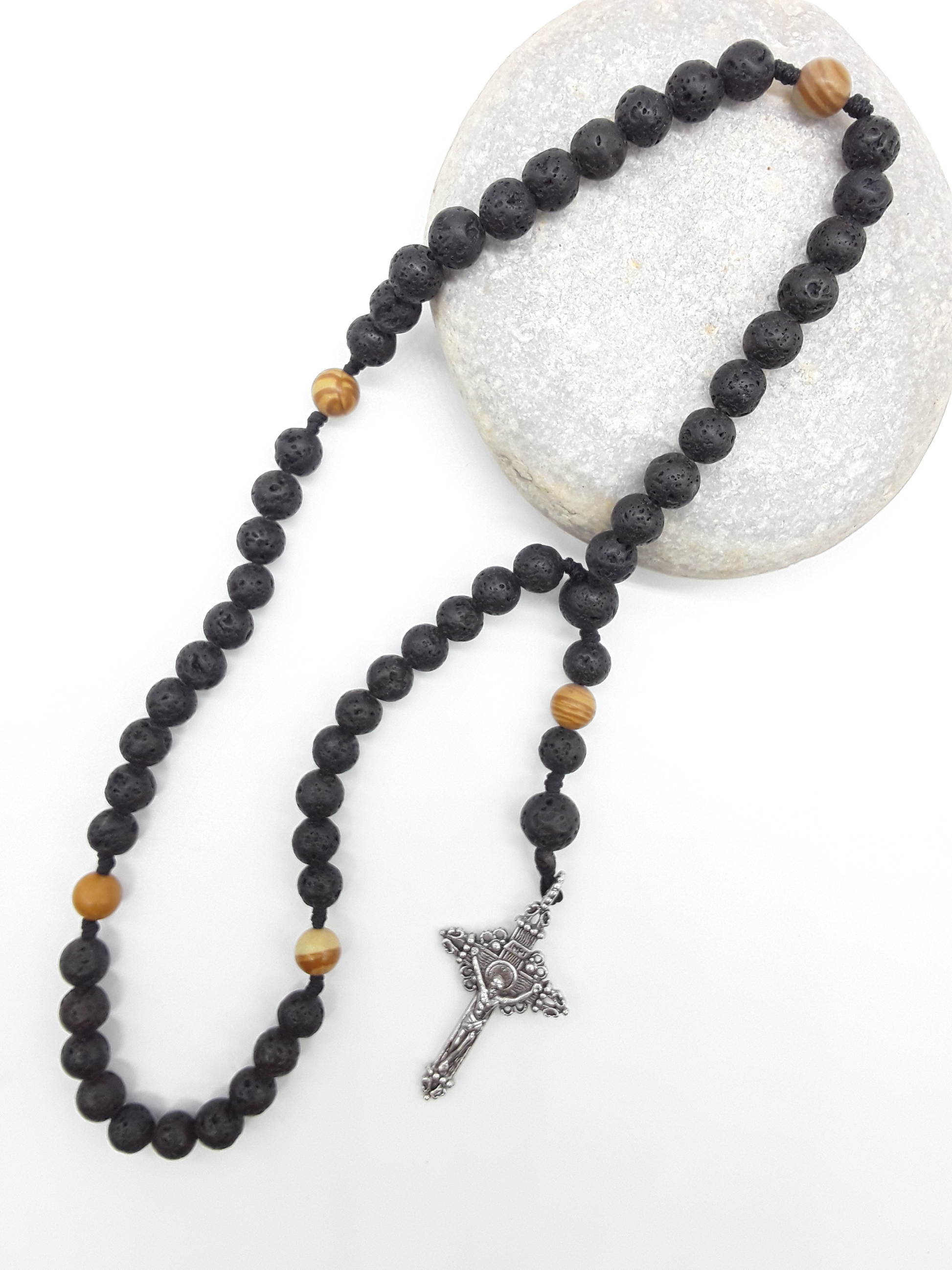 Compact Catholic Pocket Rosary in lava and tigerskin jasper placed on a stone surface, featuring a textured tin crucifix.