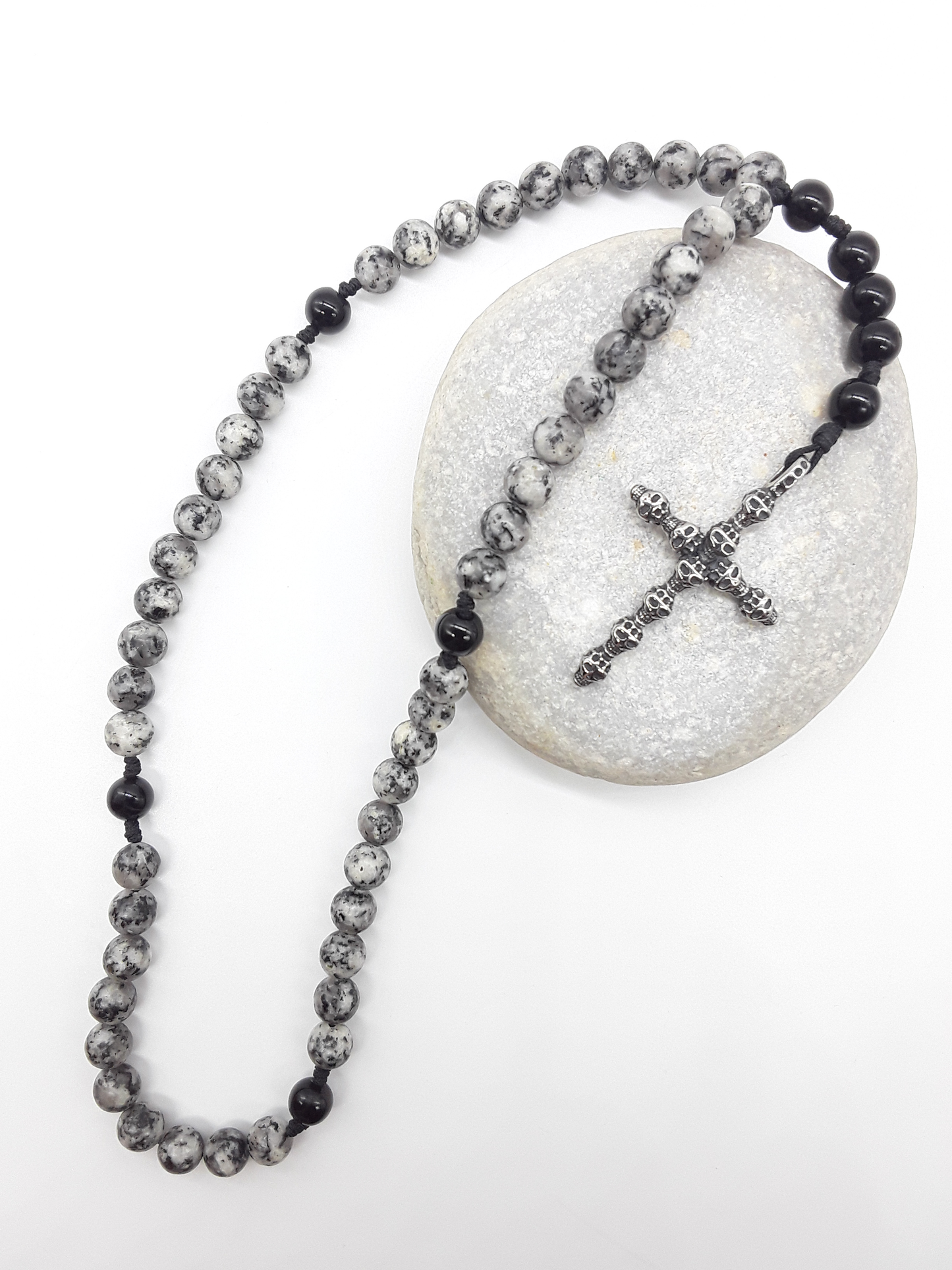 Pocket Catholic Rosary with jasper and black onyx beads resting on stone surface, featuring a textured stainless steel cross.