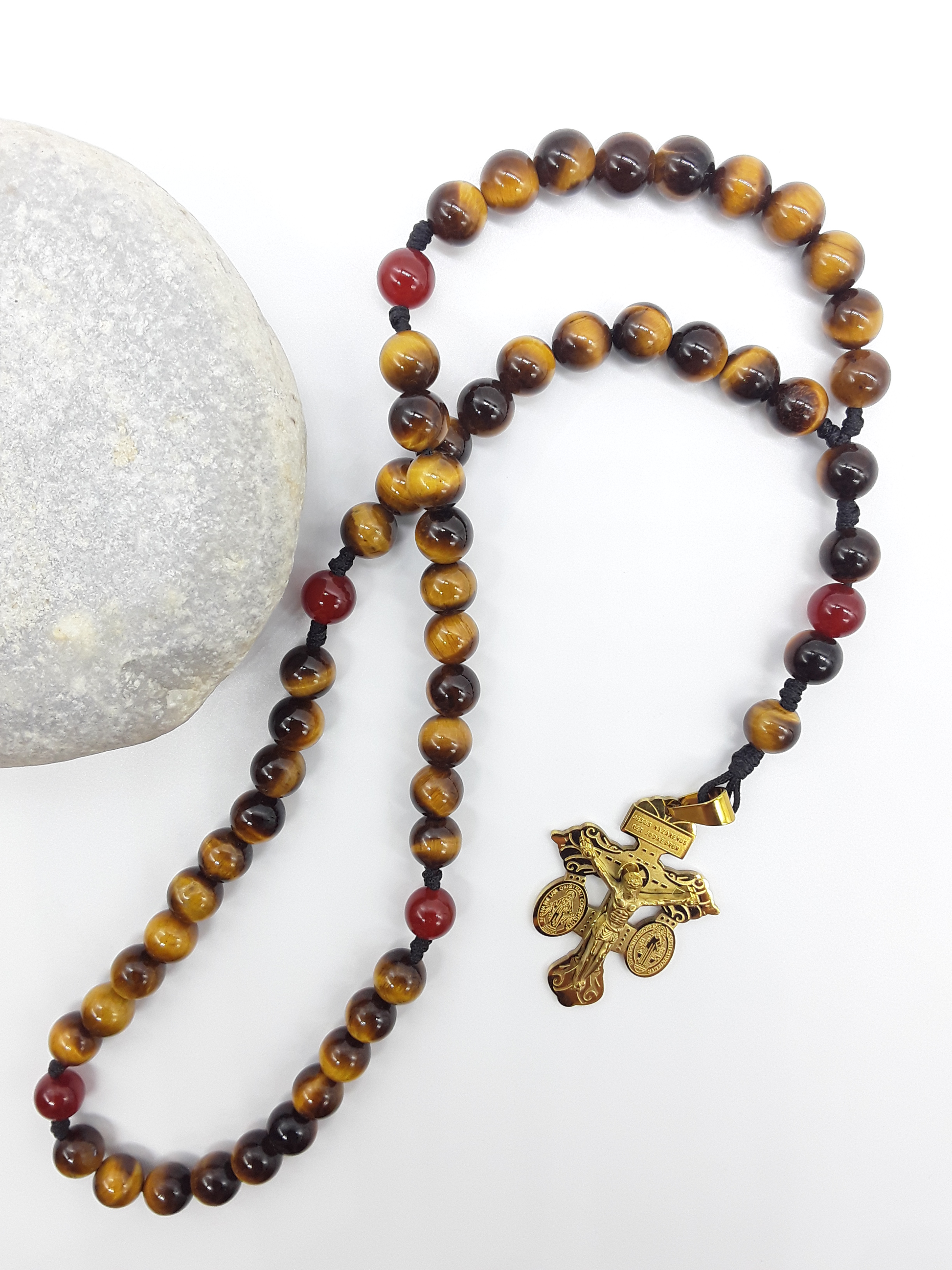 Pocket Catholic Rosary with Tiger’s Eye and Carnelian beads placed beside natural stone, featuring a steel devotional crucifix