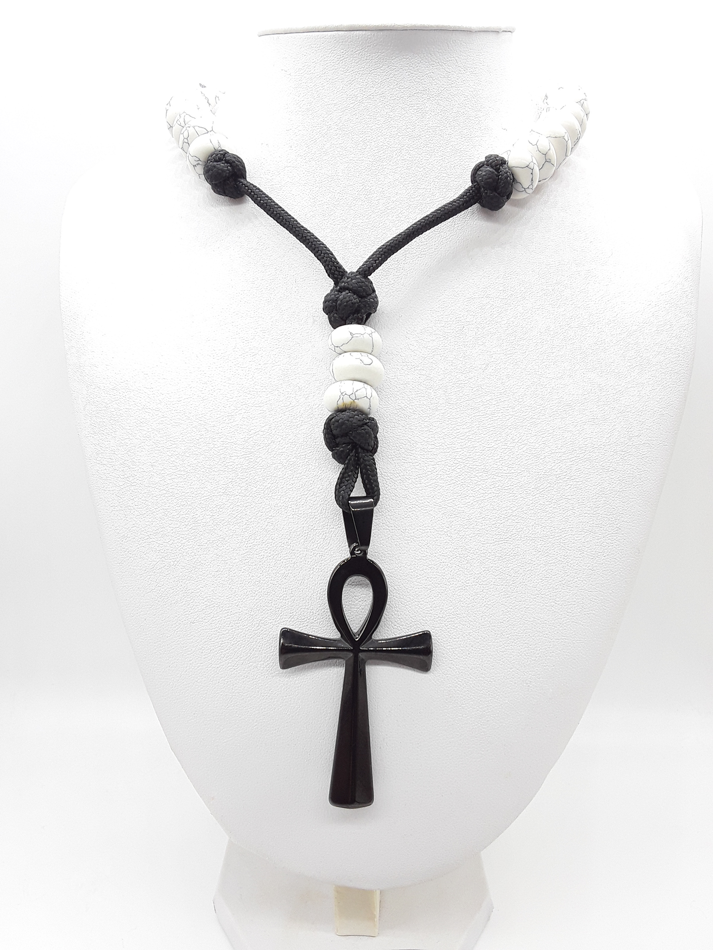 Howlite Paracord Catholic Rosary with stainless steel Ankh cross by Polmadeva resting on a mannequin.