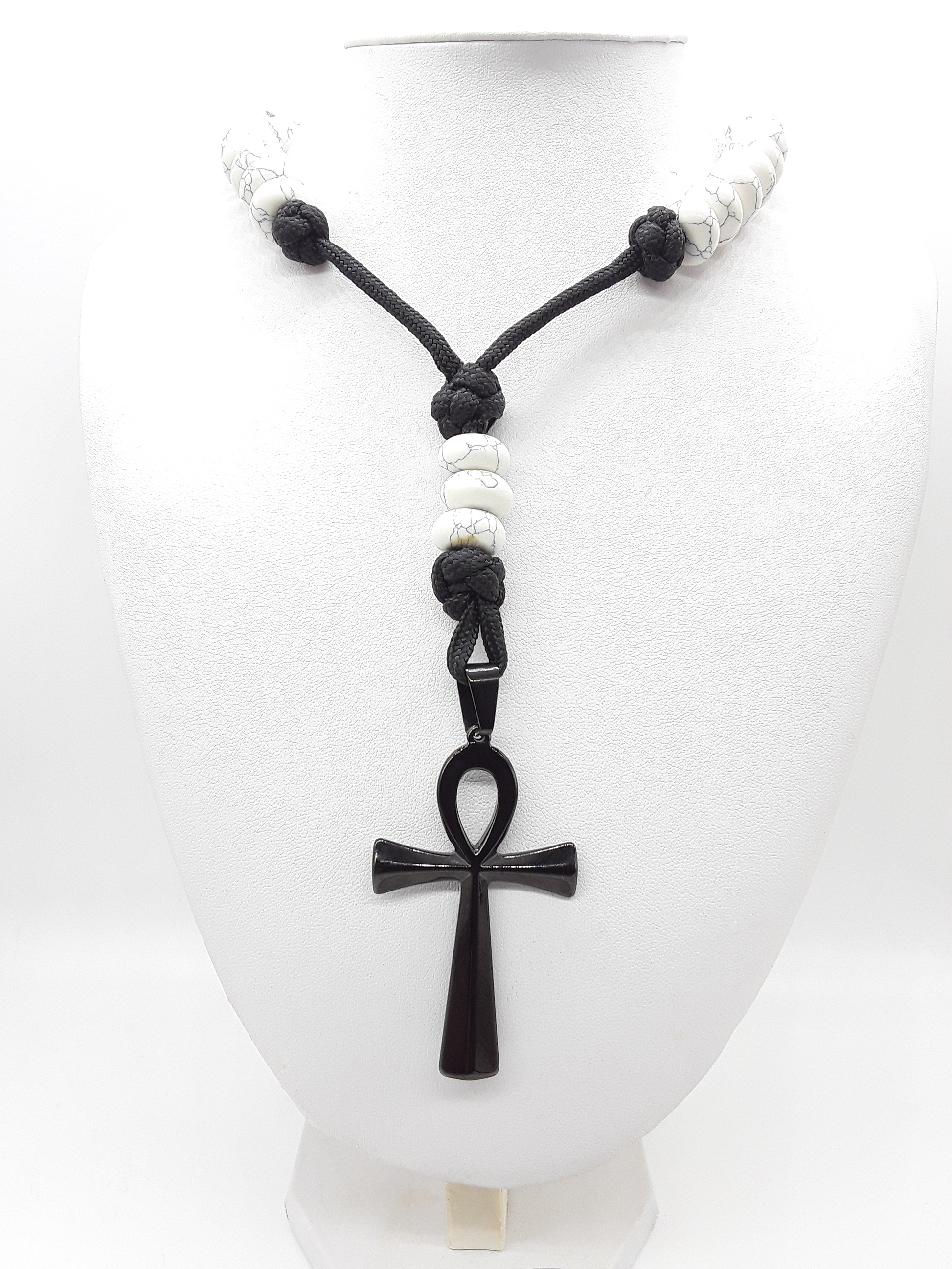 Howlite Paracord Catholic Rosary with stainless steel Ankh cross by Polmadeva resting on a mannequin.