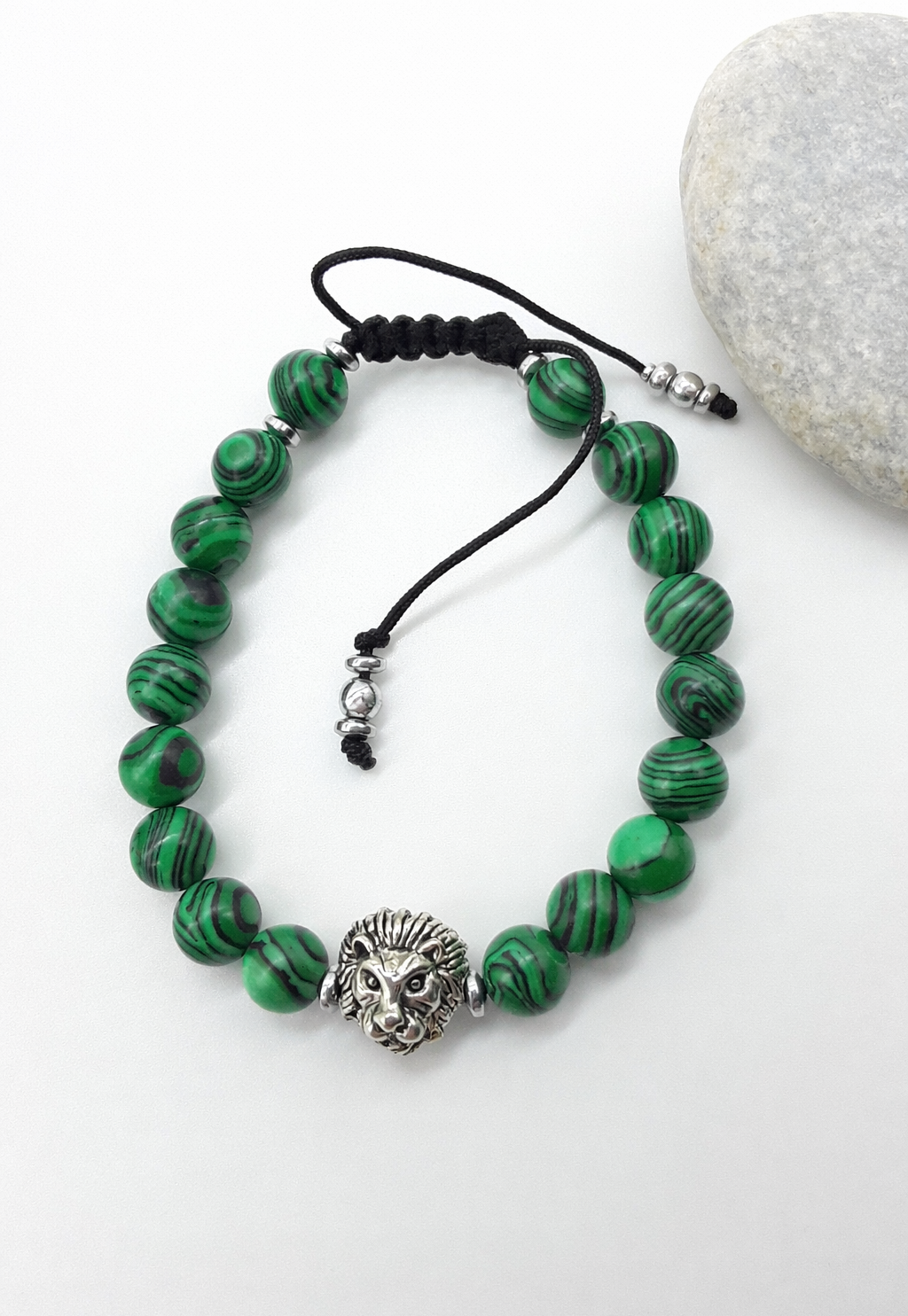 Lion bracelet with malachite beads placed beside natural stone