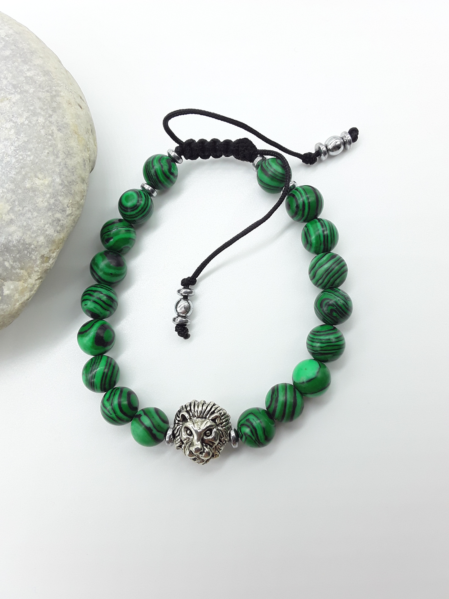 Lion bracelet with malachite beads placed beside natural stone
