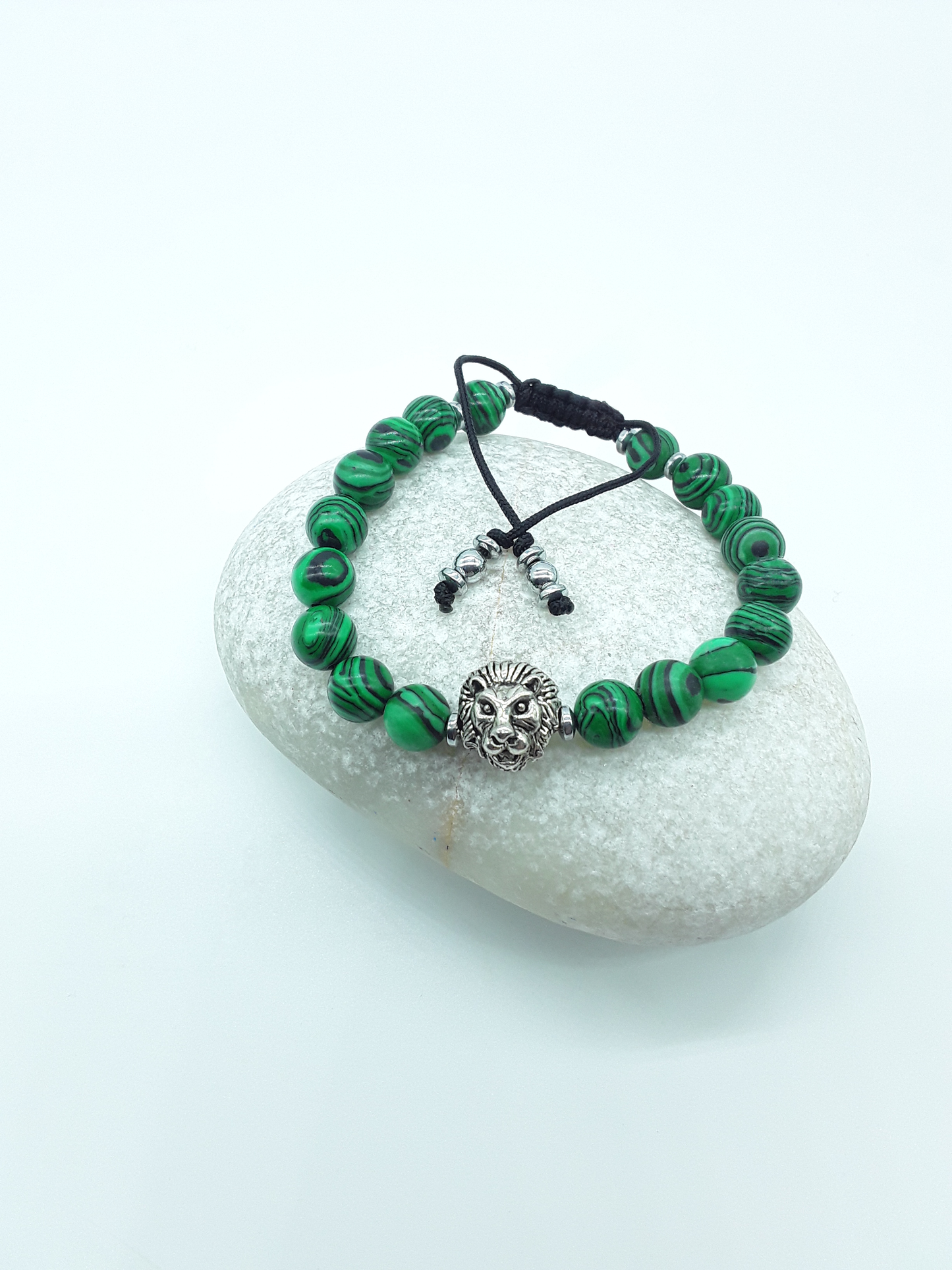 Malachite and hematite lion bracelet resting on a natural stone