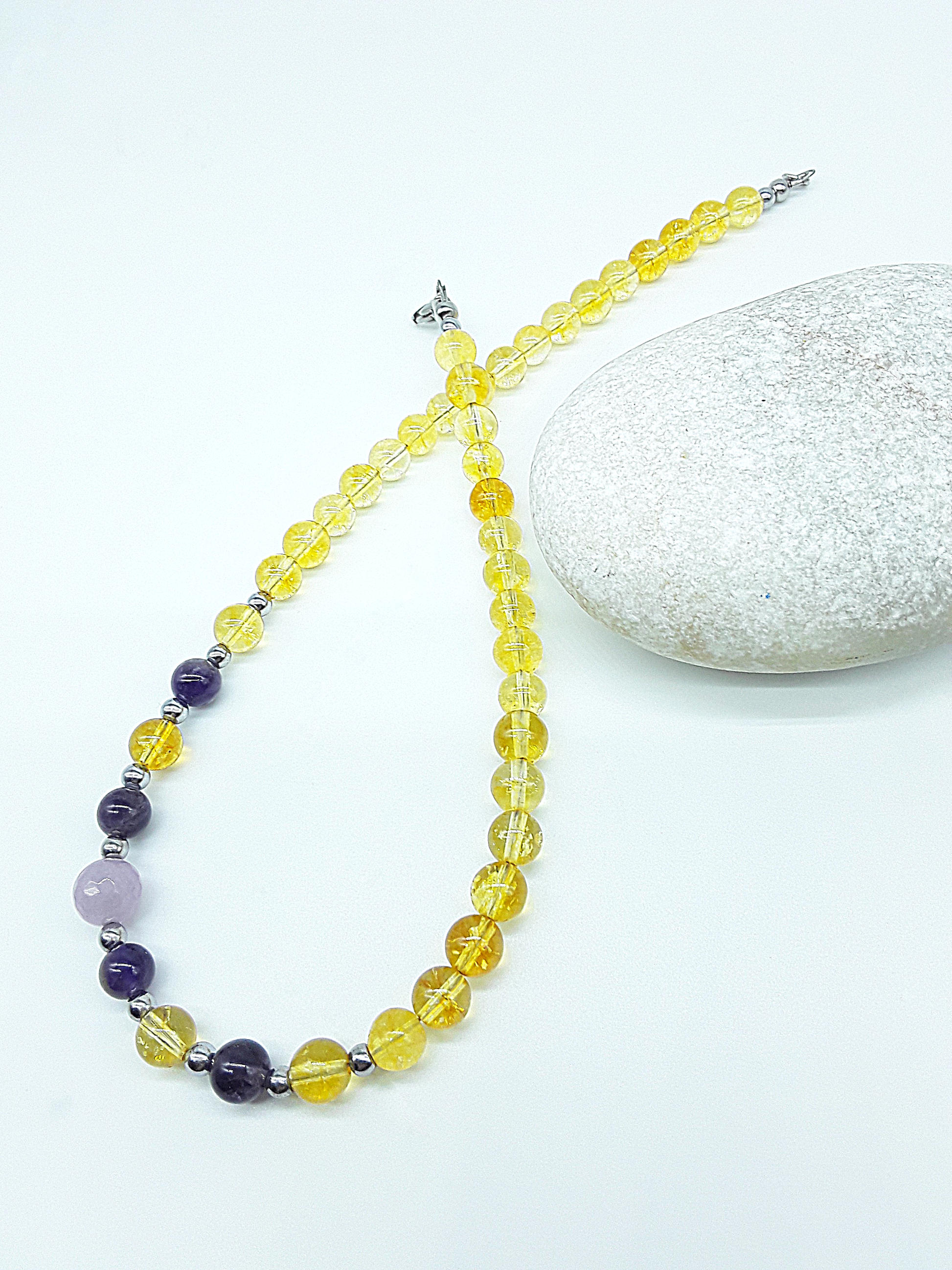 Luminous Ascent Necklace by Polmadeva with citrine, amethyst, rose quartz and hematite gemstones, arranged on a natural stone.
