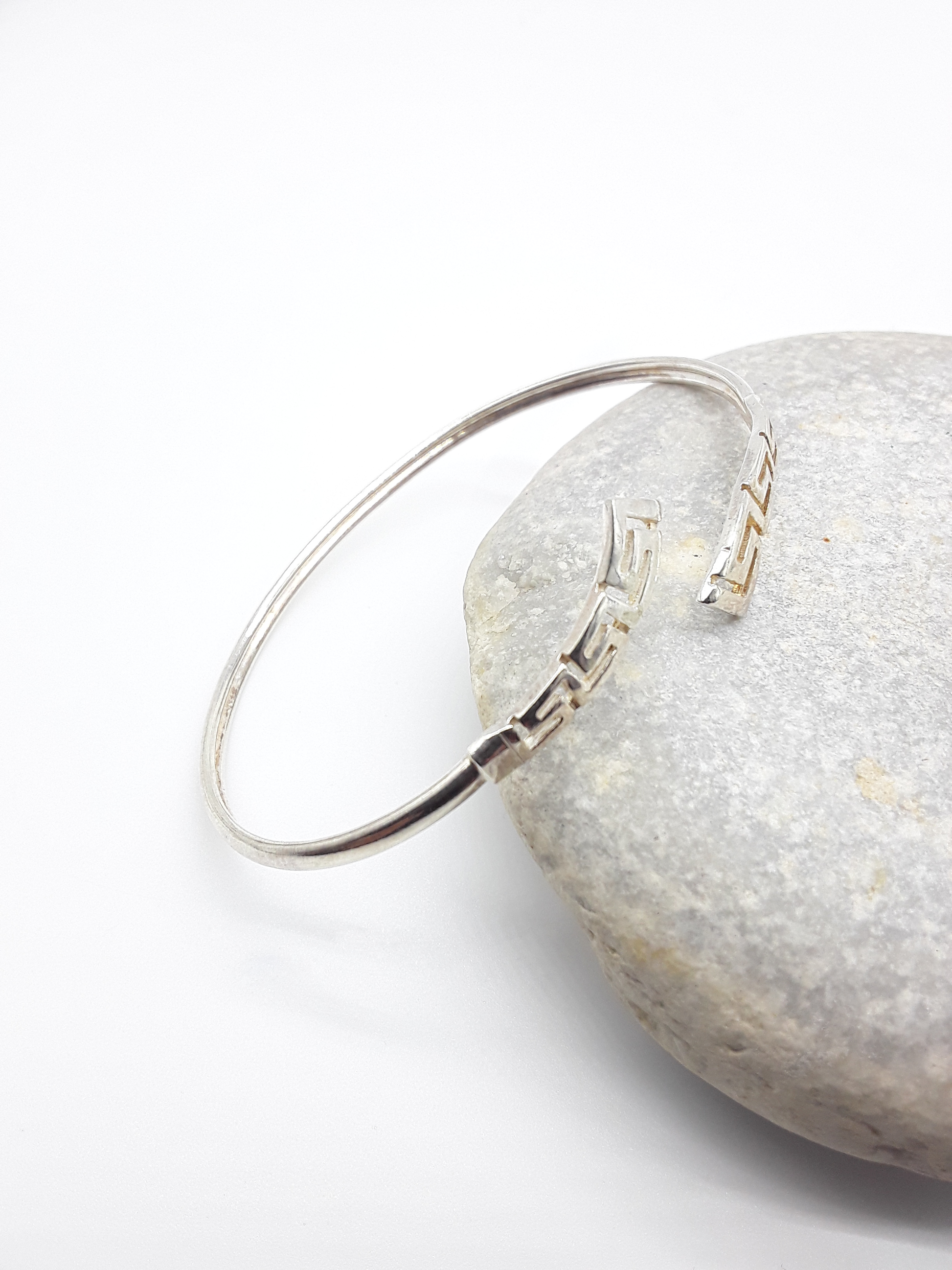 Meander Form sterling silver cuff bracelet beside stone — Polmadeva