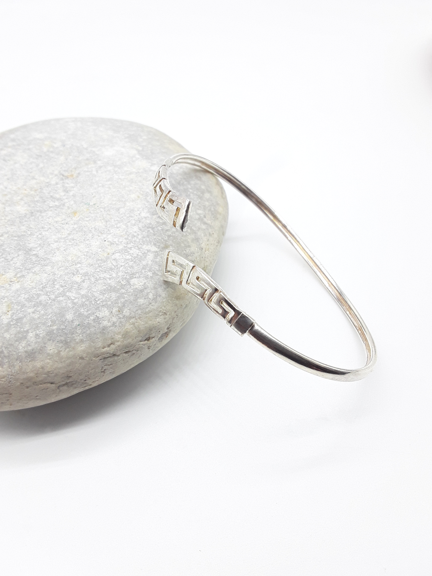 Meander Form sterling silver cuff bracelet beside stone — Polmadeva