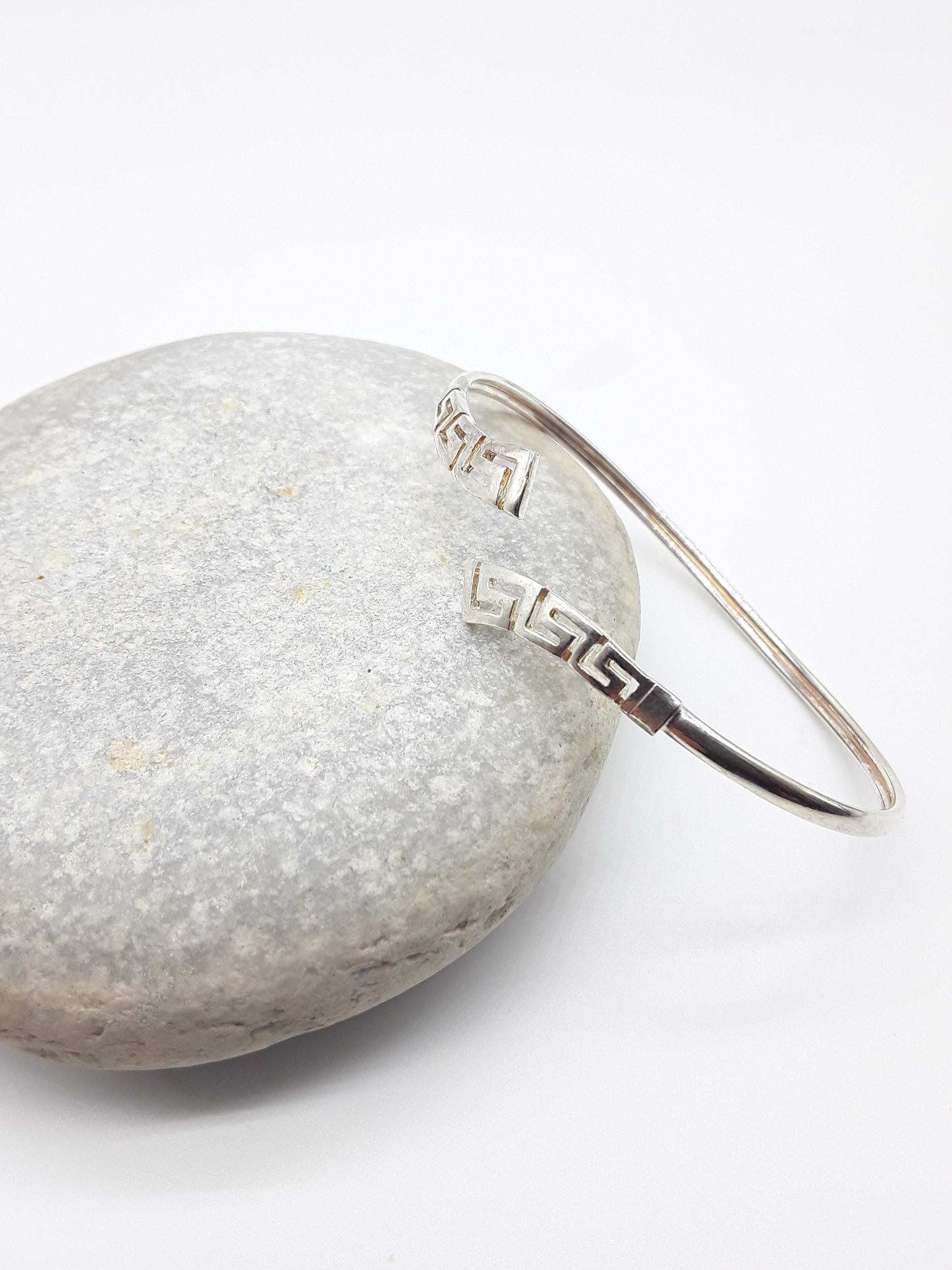 Meander Form sterling silver cuff bracelet beside stone — Polmadeva