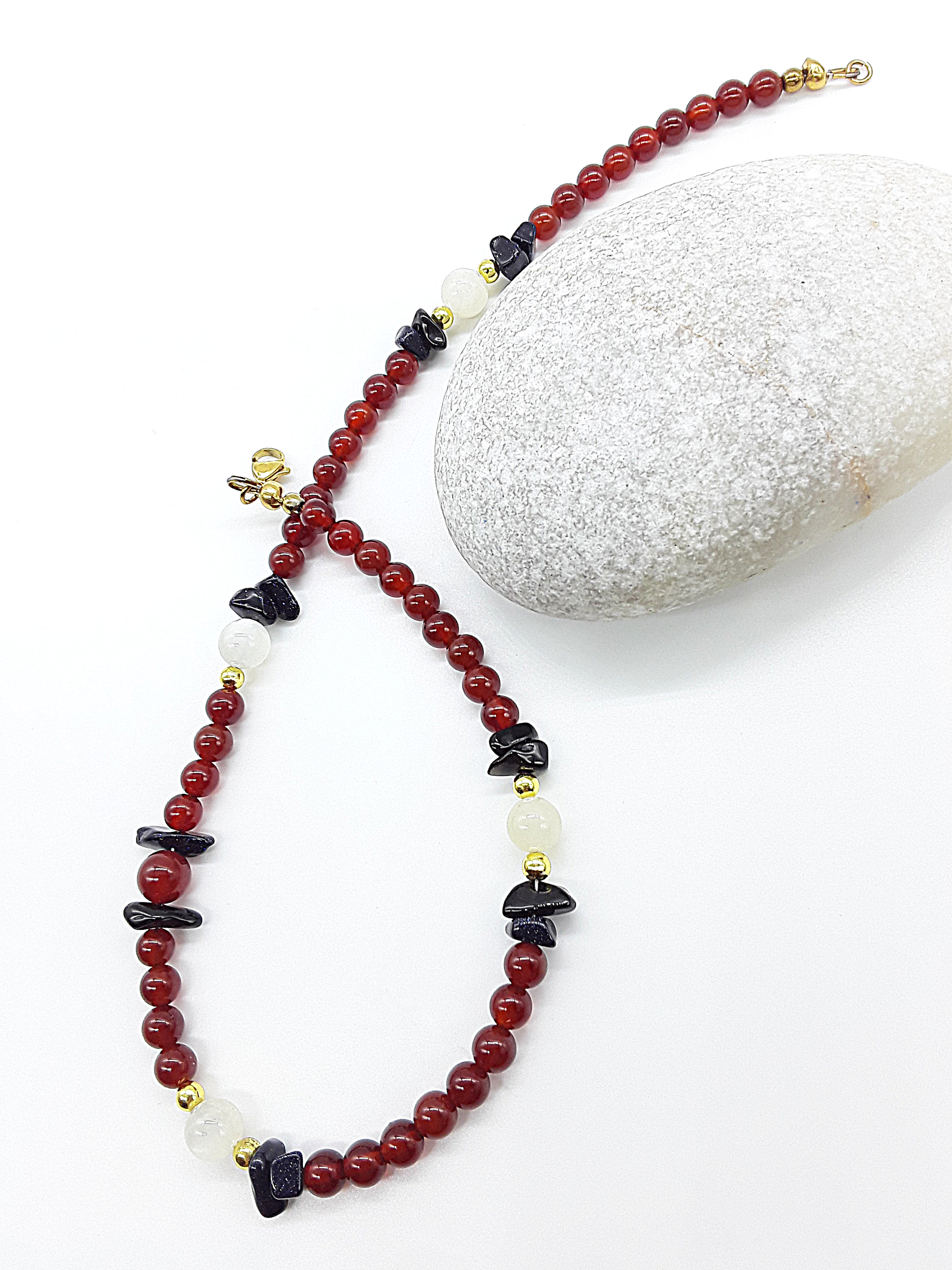 Nightfall Renewal Necklace by Polmadeva laid flat, highlighting carnelian beads, moonstone and blue goldstone details, Begin Again collection