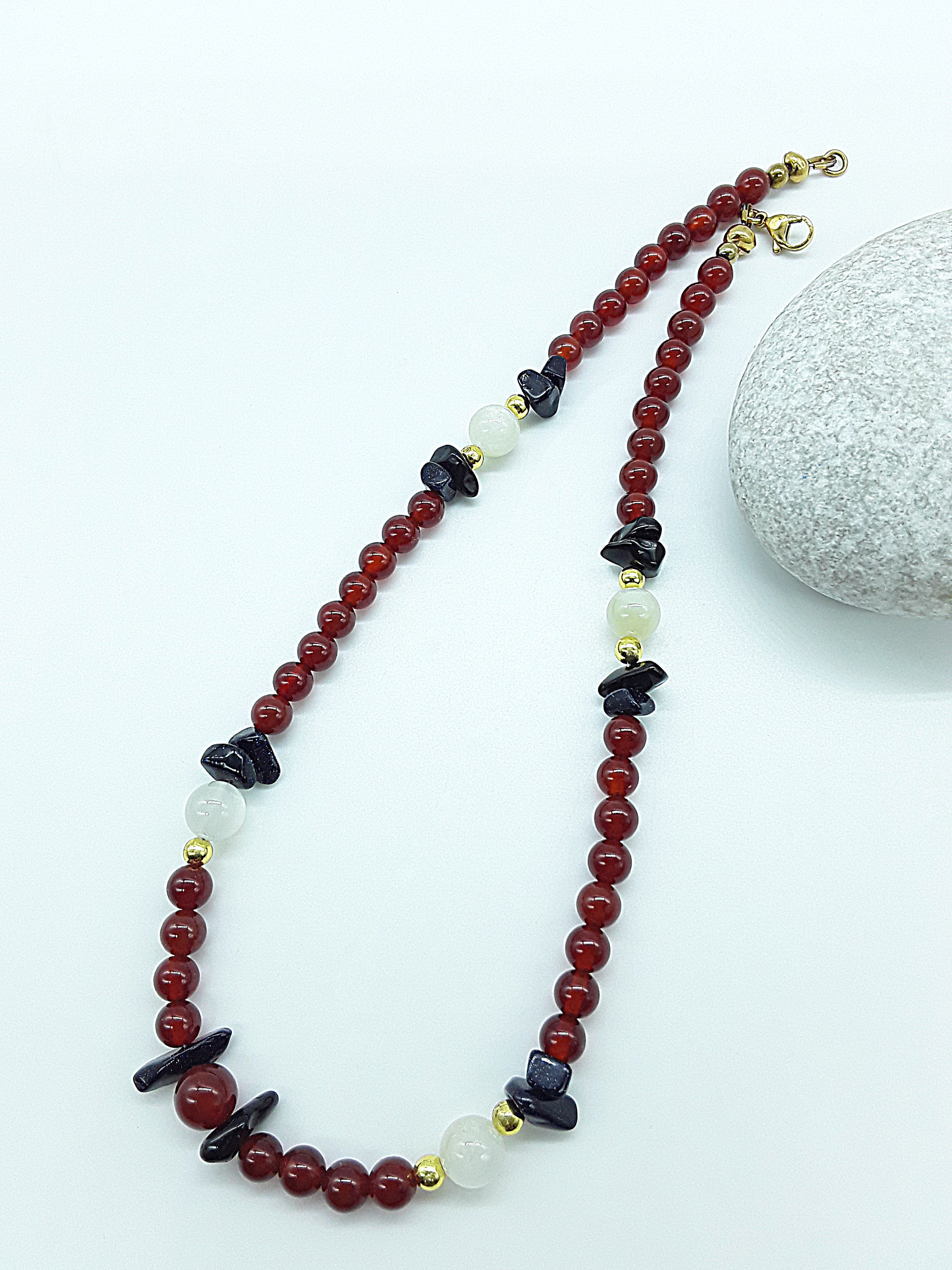 Nightfall Renewal Necklace by Polmadeva laid flat in a flowing arrangement with carnelian, moonstone and blue goldstone, Begin Again collection