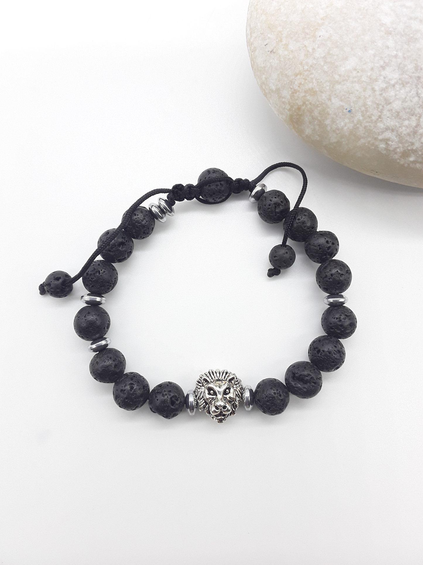 Lava stone lion bracelet beside natural stone, highlighting balance, resilience, and quiet authority